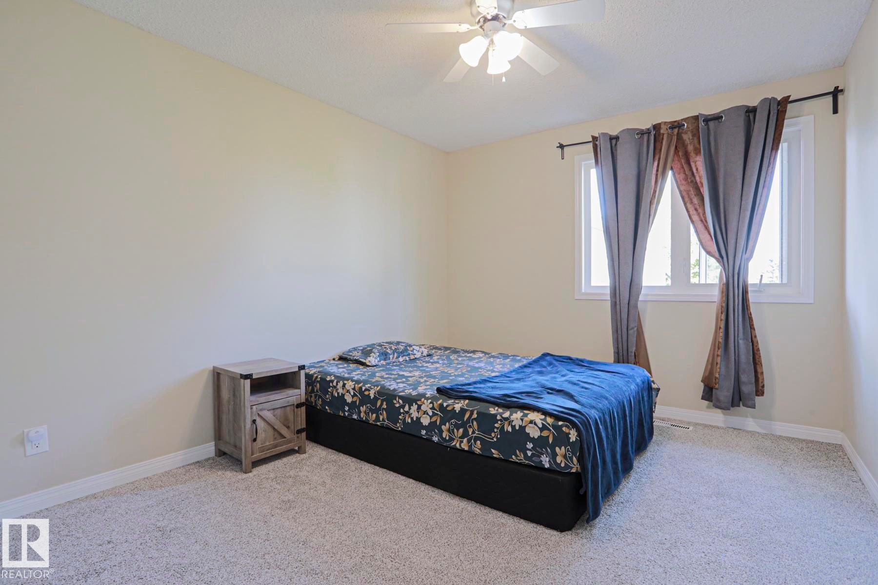 Neutral wall color, ceiling-mounted light fixture with fan, large window with white frame, and wall-to-wall carpeting - 319 Telford Court, Leduc, AB