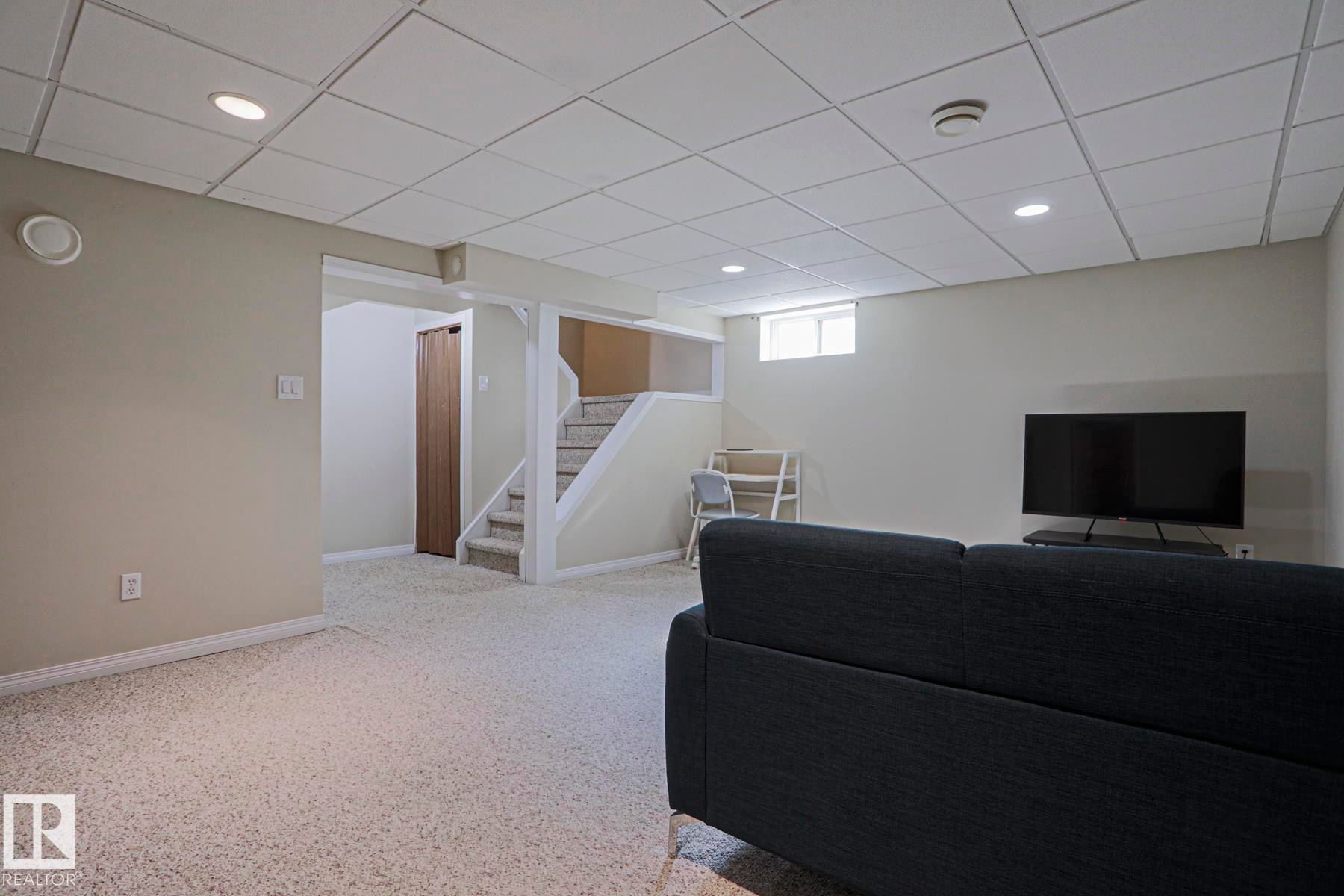 Recessed lighting, drop ceiling, neutral wall tones, light-colored carpeting, and a window - 319 Telford Court, Leduc, AB