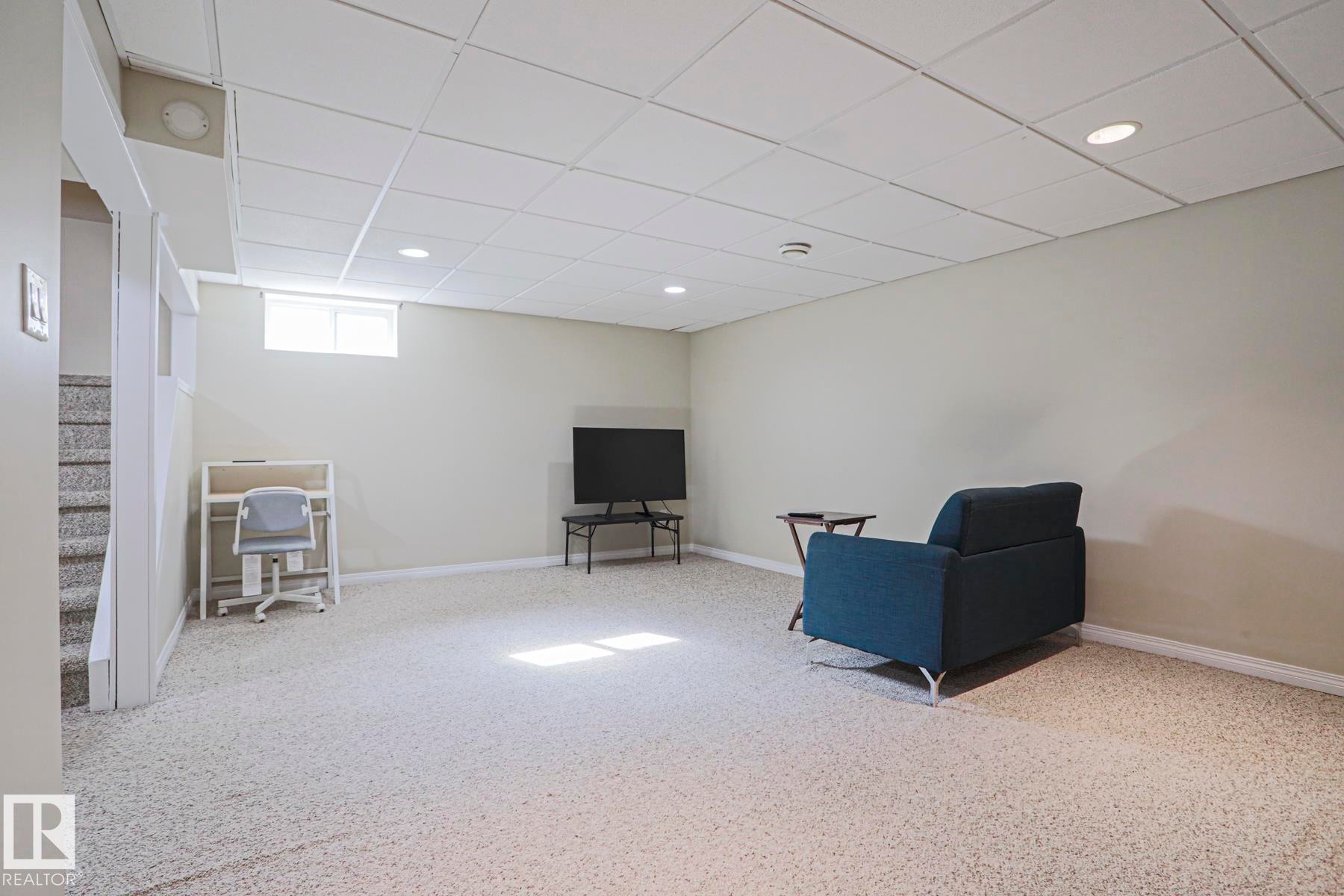 Recessed lighting illuminates a spacious room featuring wall-to-wall carpeting and a drop ceiling - 319 Telford Court, Leduc, AB