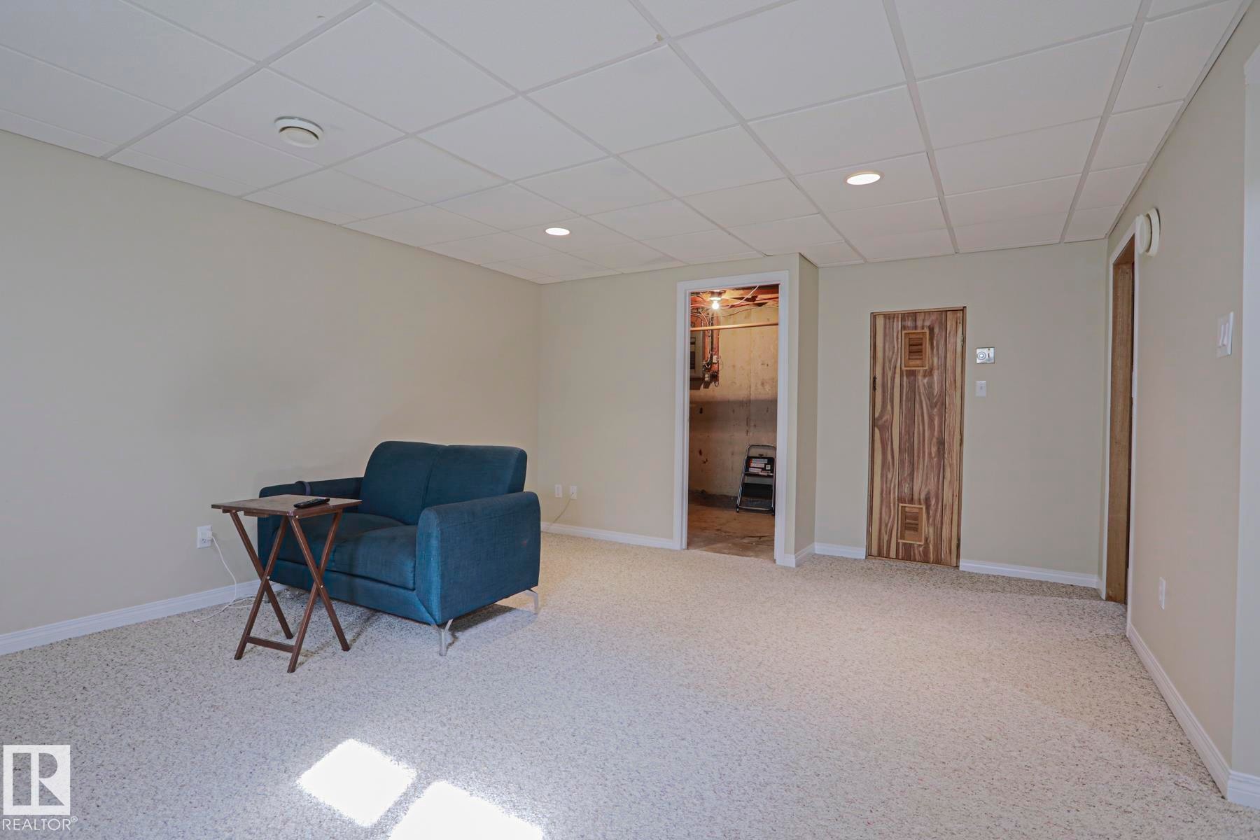 Recessed lighting, drop ceiling, light-colored carpeting, neutral wall finishes, and a wood-paneled door - 319 Telford Court, Leduc, AB