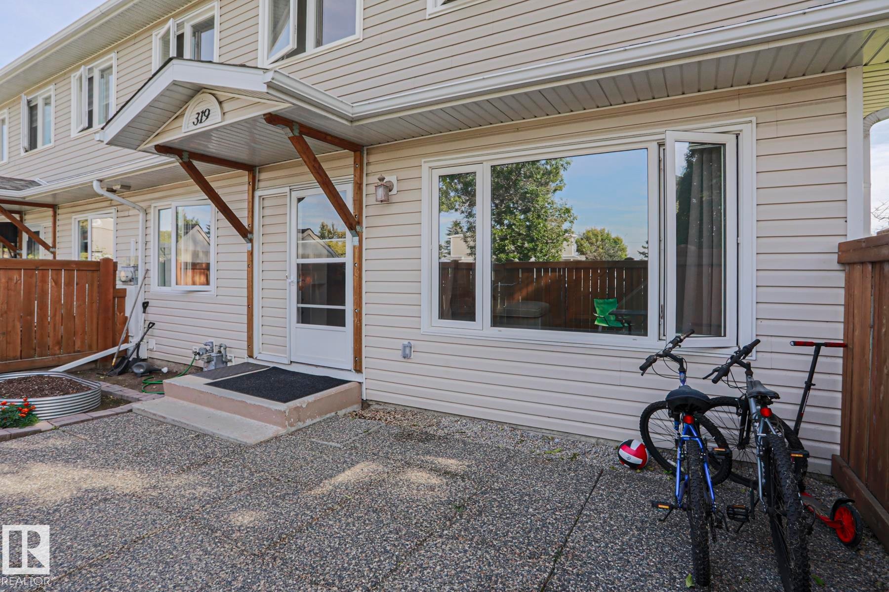 Exterior entry featuring a covered porch, durable siding, and expansive window - 319 Telford Court, Leduc, AB