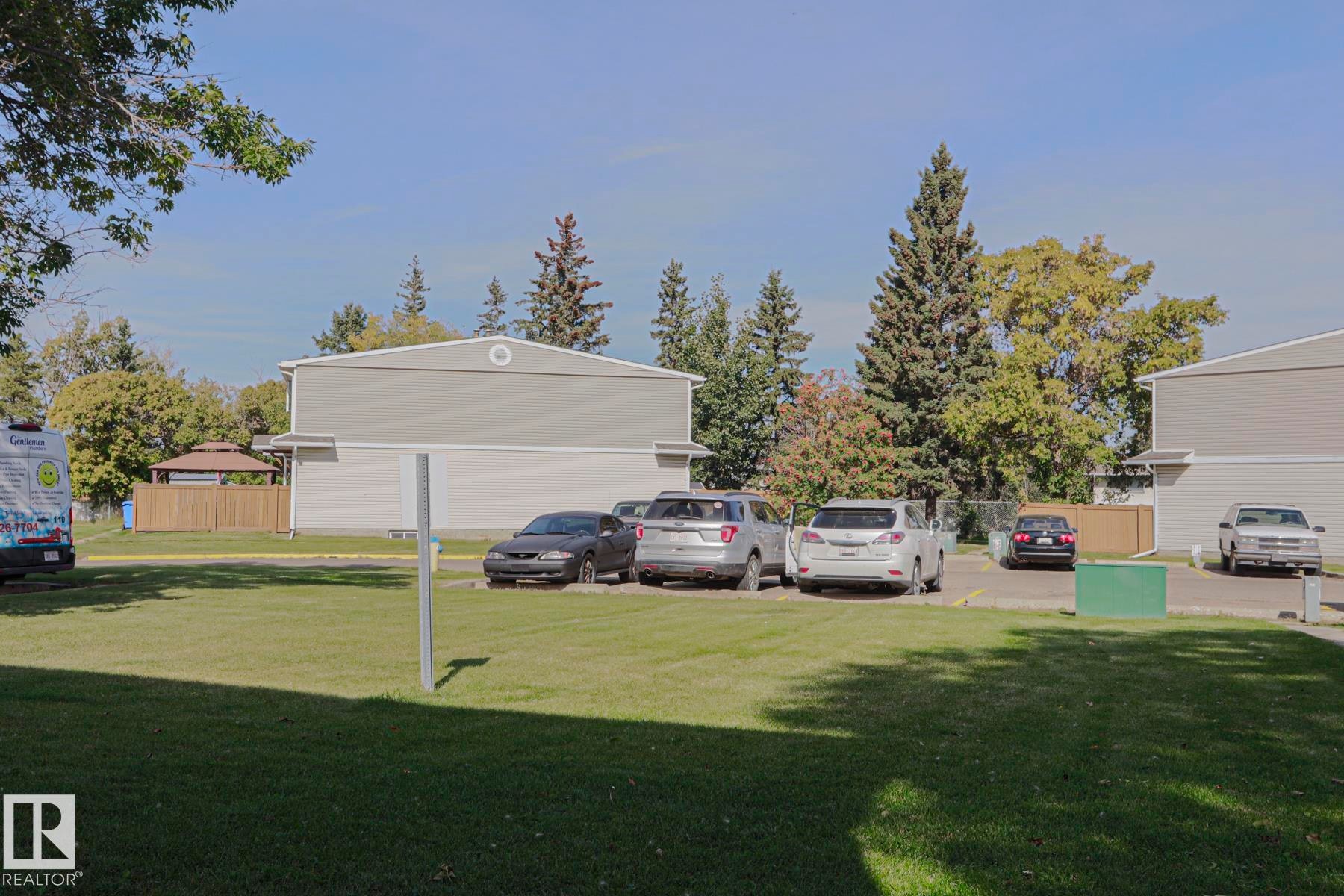 Expansive green space featuring mature trees and a fenced gazebo structure - 319 Telford Court, Leduc, AB