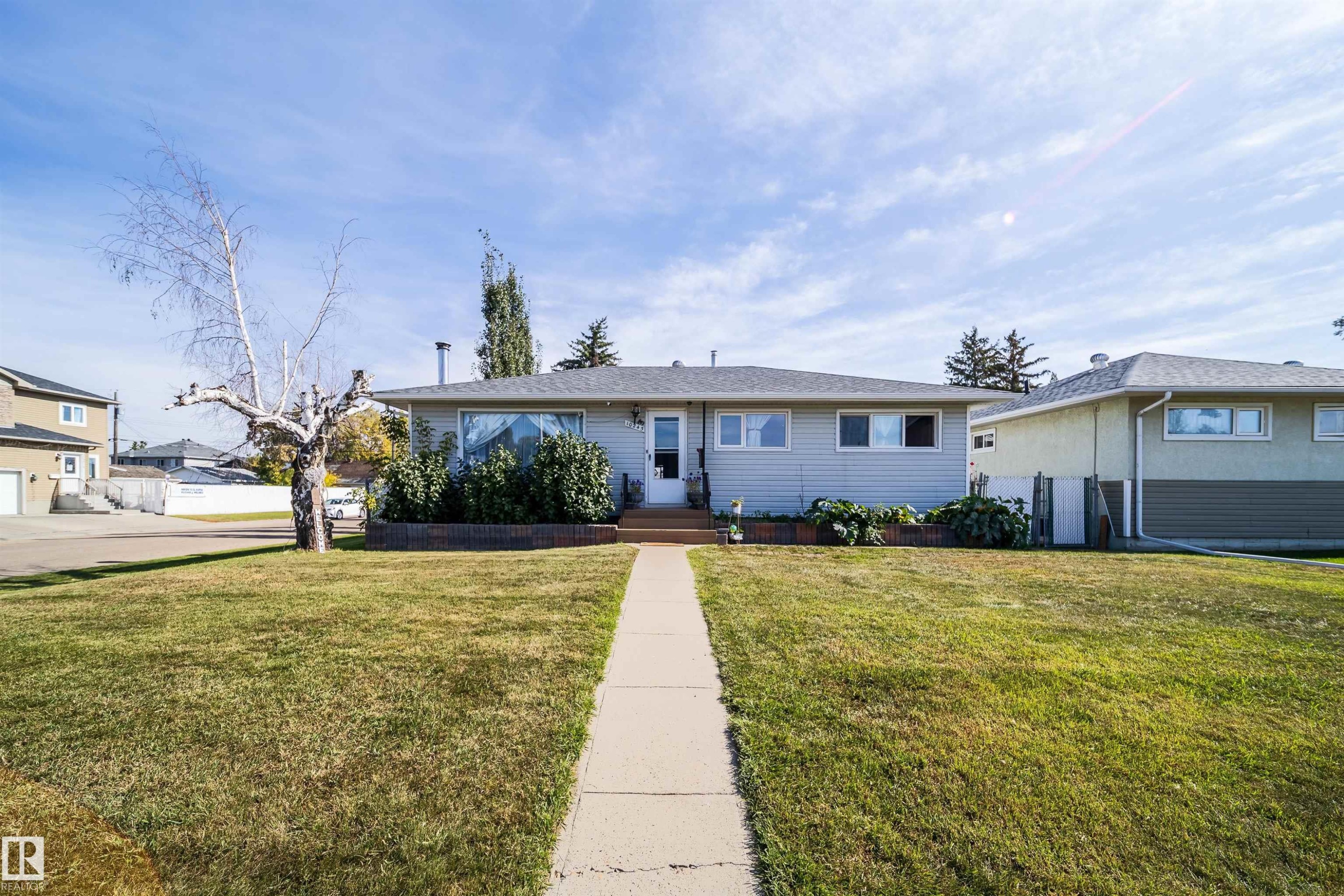 Single-story residence with a light-toned exterior siding, a front yard featuring a concrete walkway, and established landscaping - 10245 160 Street Nw, Edmonton, AB