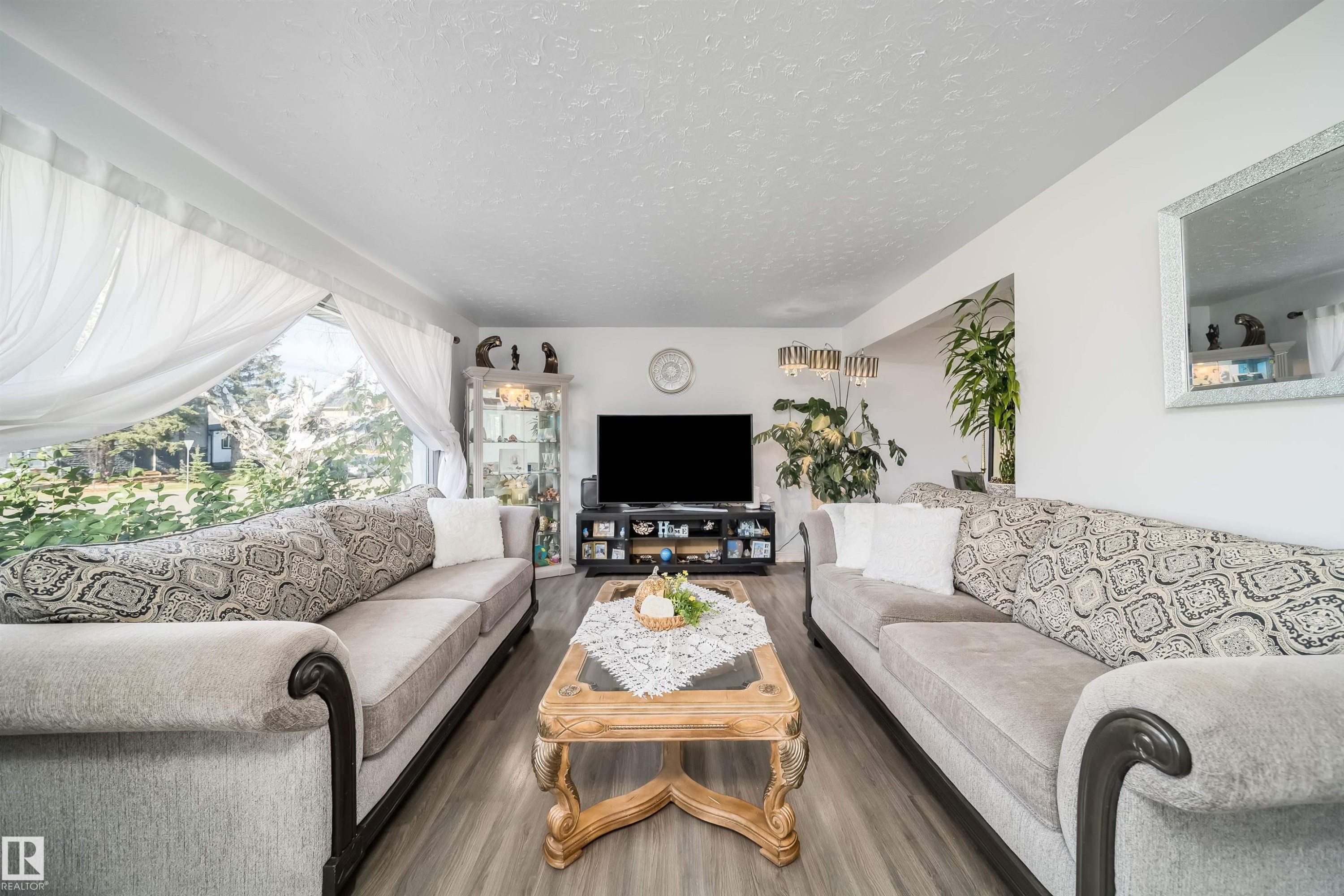 Expansive window providing abundant natural light, wood-finish flooring, and white painted walls - 10245 160 Street Nw, Edmonton, AB