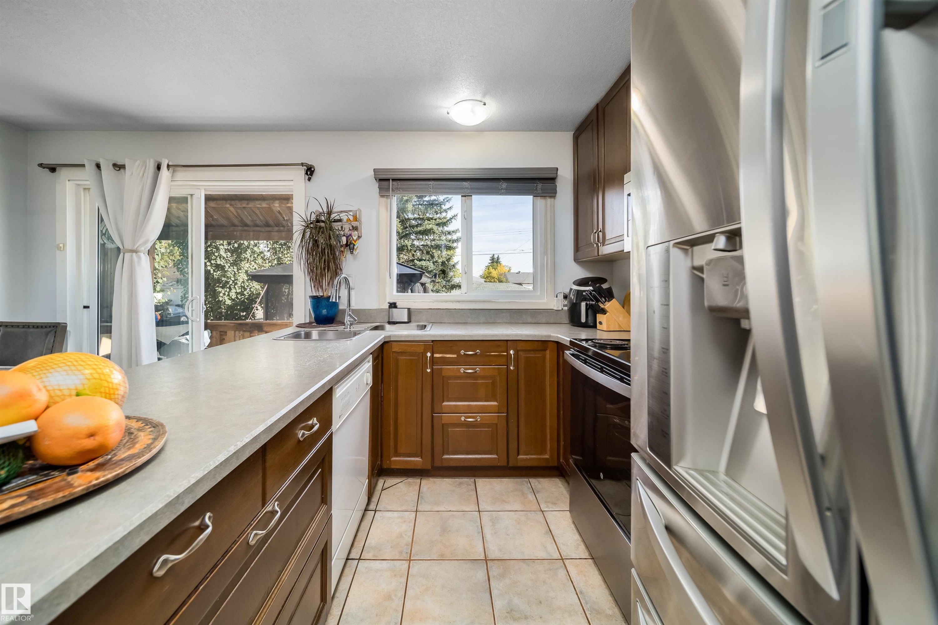 Kitchen featuring wood-finish cabinetry, light-toned countertops, and tile flooring - 10245 160 Street Nw, Edmonton, AB