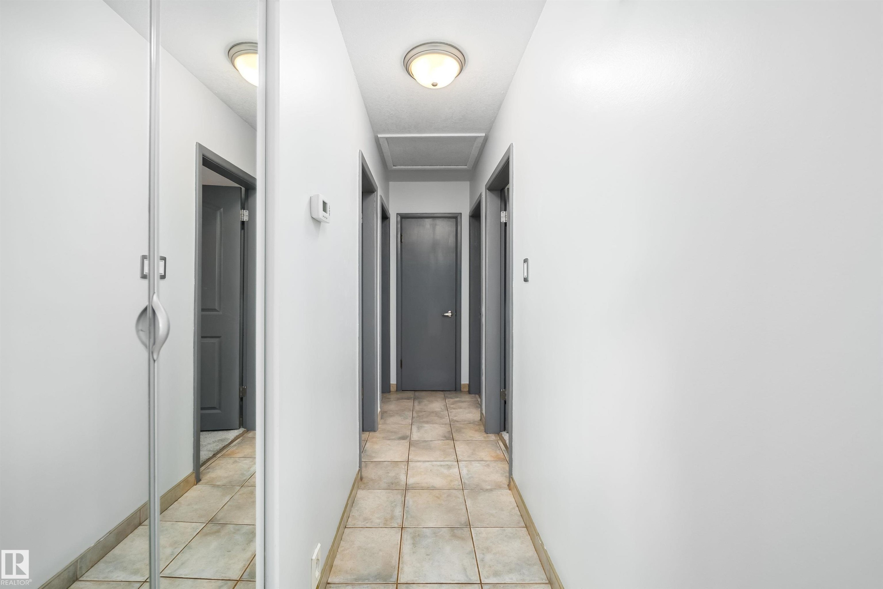 Hallway featuring tile flooring, flush mount lighting, and neutral wall tones - 10245 160 Street Nw, Edmonton, AB