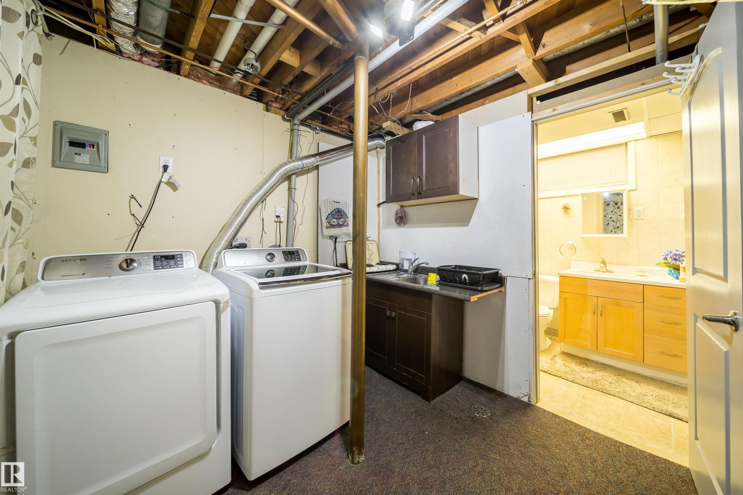 Laundry area featuring a utility sink, dark wood-finish cabinetry, and exposed ceiling joists - 10245 160 Street Nw, Edmonton, AB