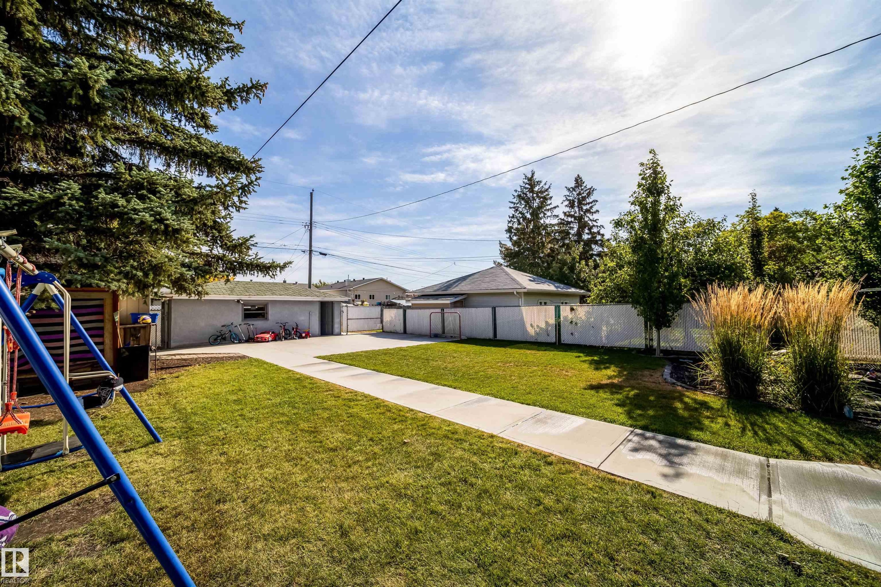 Expansive backyard with a manicured lawn, concrete pathway, and mature landscaping - 10245 160 Street Nw, Edmonton, AB