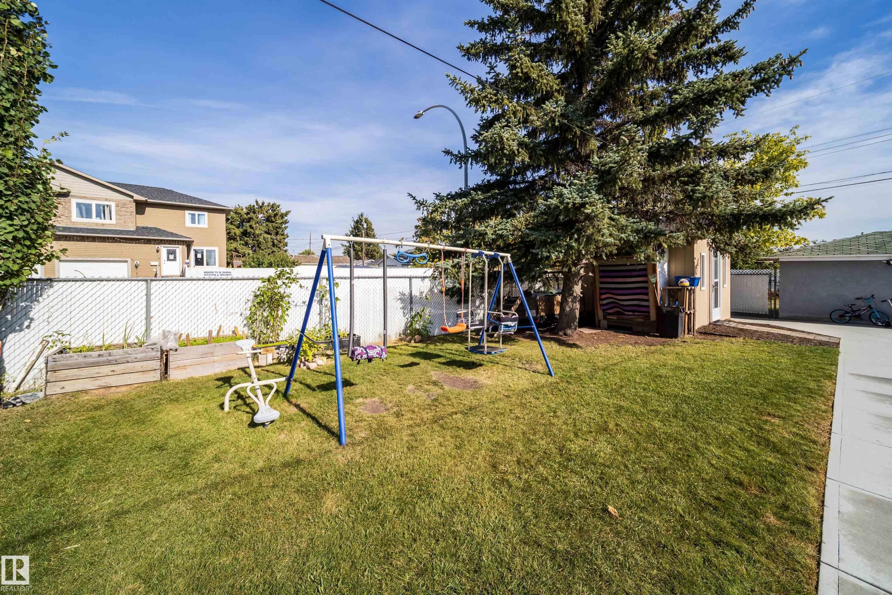 Grassed backyard featuring a chain-link fence, a storage shed, and mature trees - 10245 160 Street Nw, Edmonton, AB