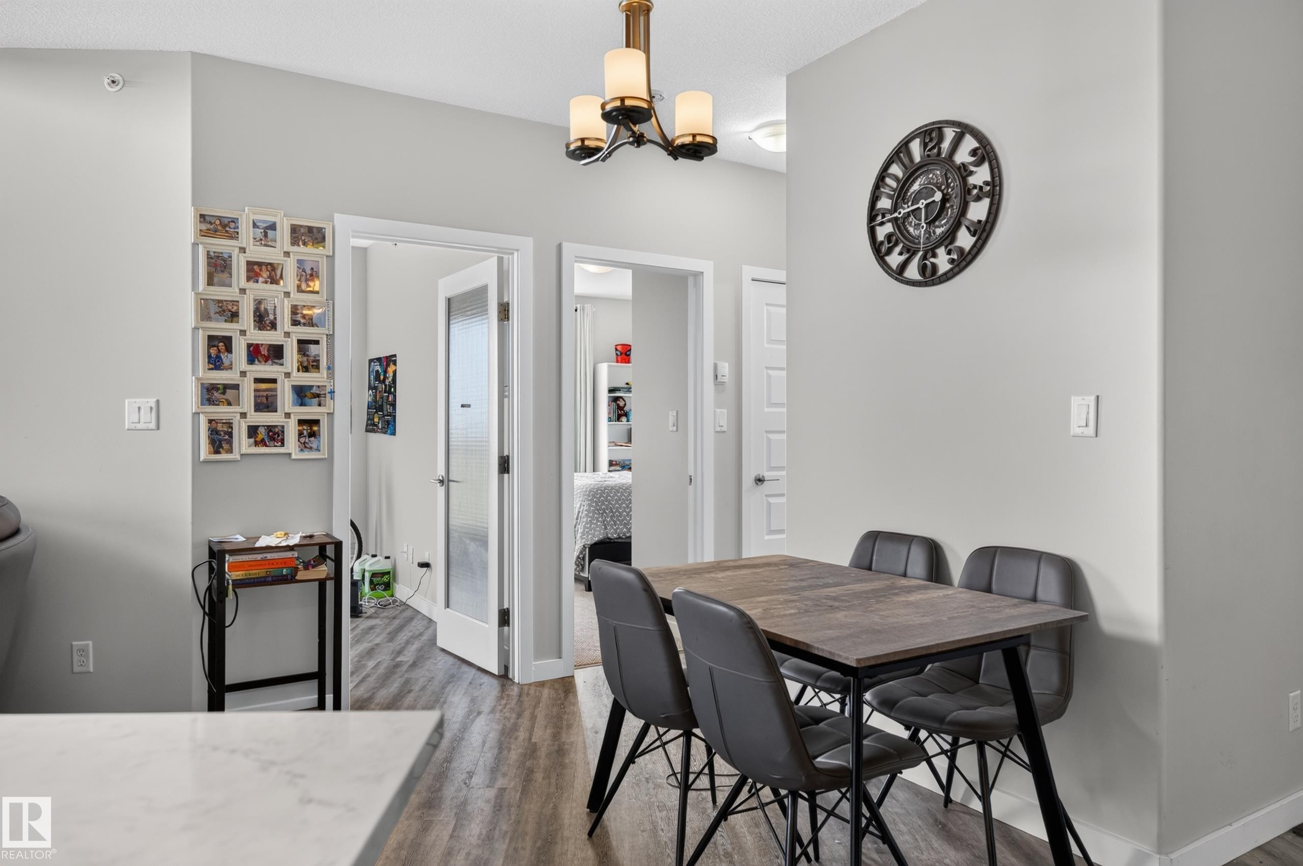 Laminate wood-finish flooring throughout, light gray wall paint, and a modern ceiling fixture - #411 304 Ambleside Link Li Sw, Edmonton, AB