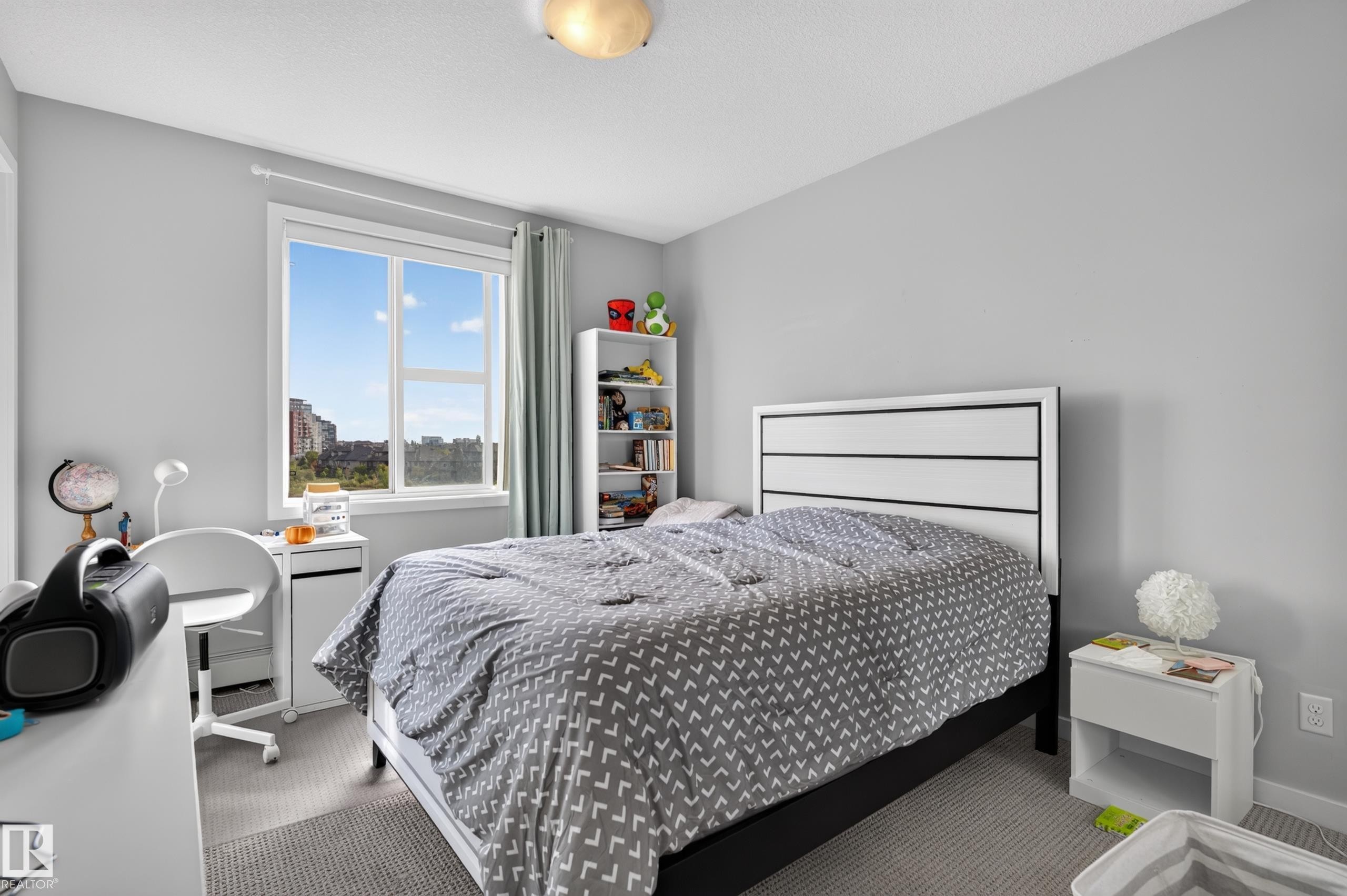 Recessed ceiling light fixture, window with white trim, built-in shelving, white headboard with black accents, and light gray wall paint - #411 304 Ambleside Link Li Sw, Edmonton, AB