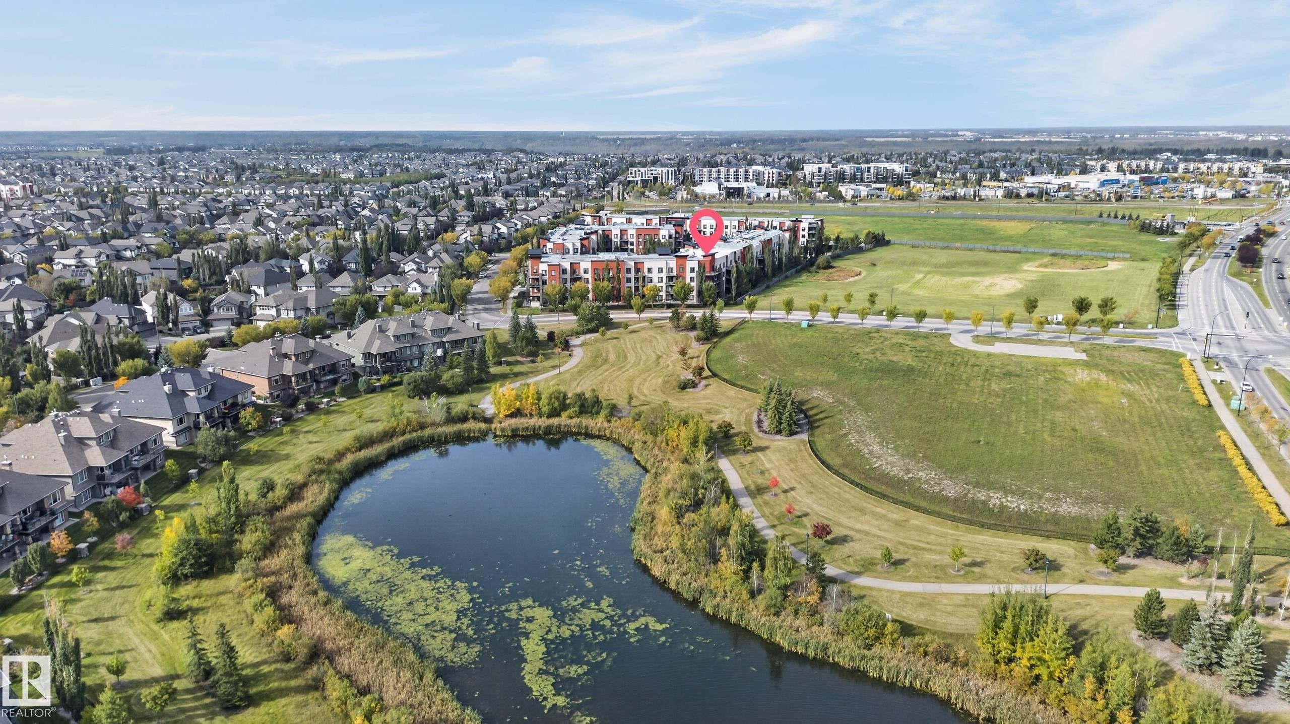 Residential development featuring a natural pond, established green spaces, and a multi-story building - #411 304 Ambleside Link Li Sw, Edmonton, AB