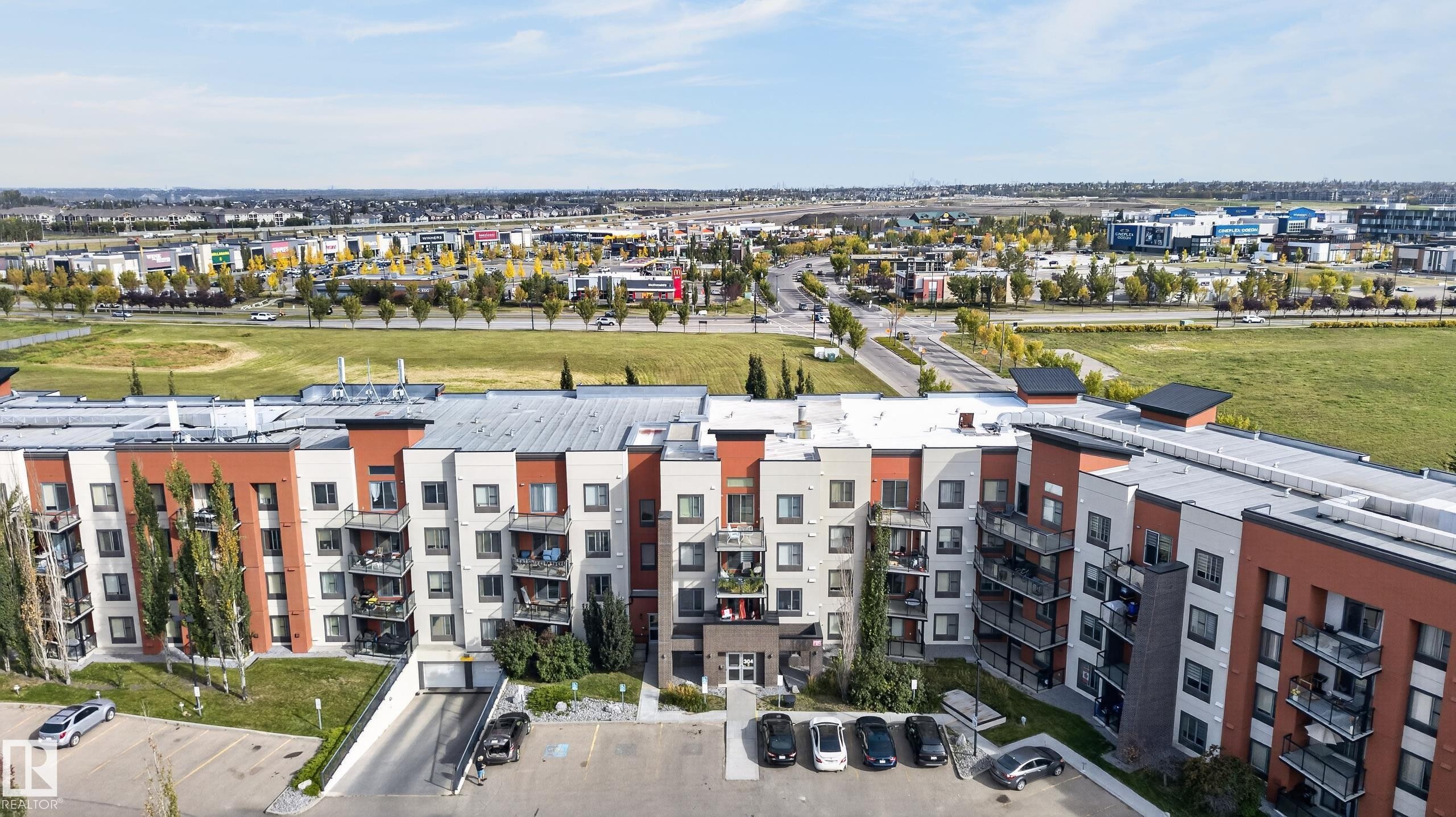 Multi-story residential building with various exterior finishes, multiple balconies, and an underground parking entrance - #411 304 Ambleside Link Li Sw, Edmonton, AB