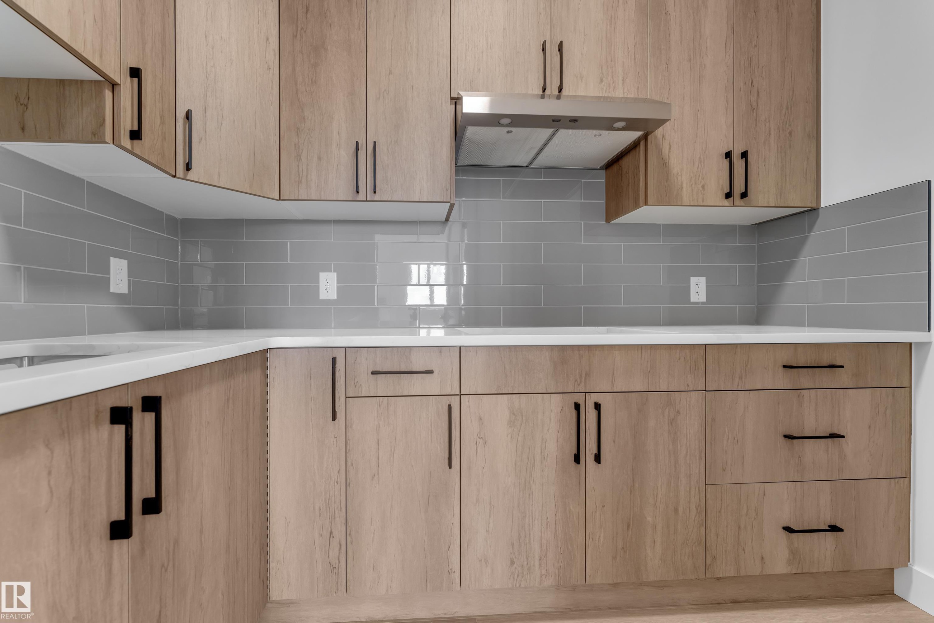 Light wood-finish cabinetry with matte black hardware, white countertops, and a gray subway tile backsplash - 4212 63 Street, Beaumont, AB