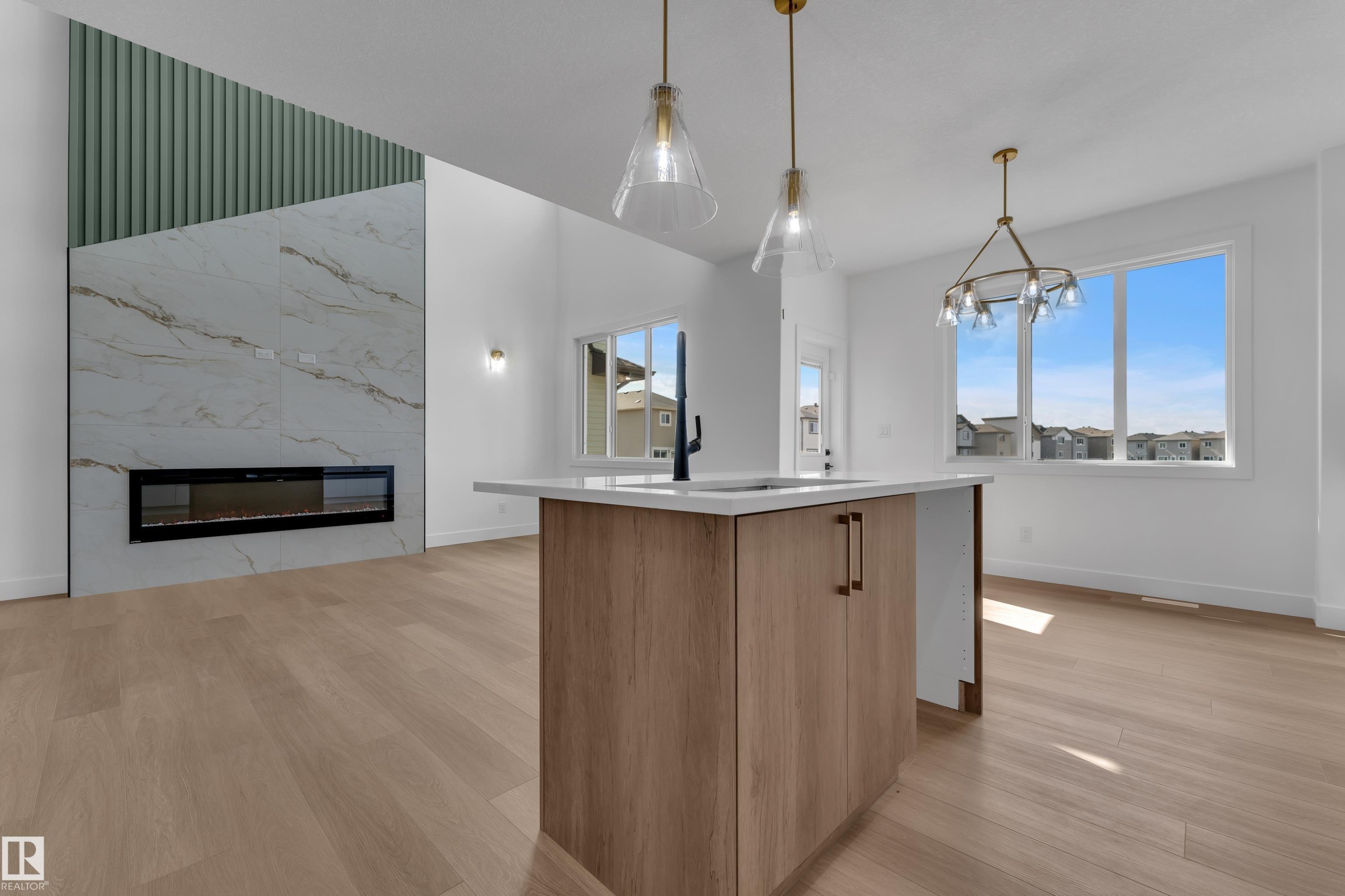 Wood-finish flooring throughout, featuring a kitchen island with light-toned cabinetry and a white countertop - 4212 63 Street, Beaumont, AB
