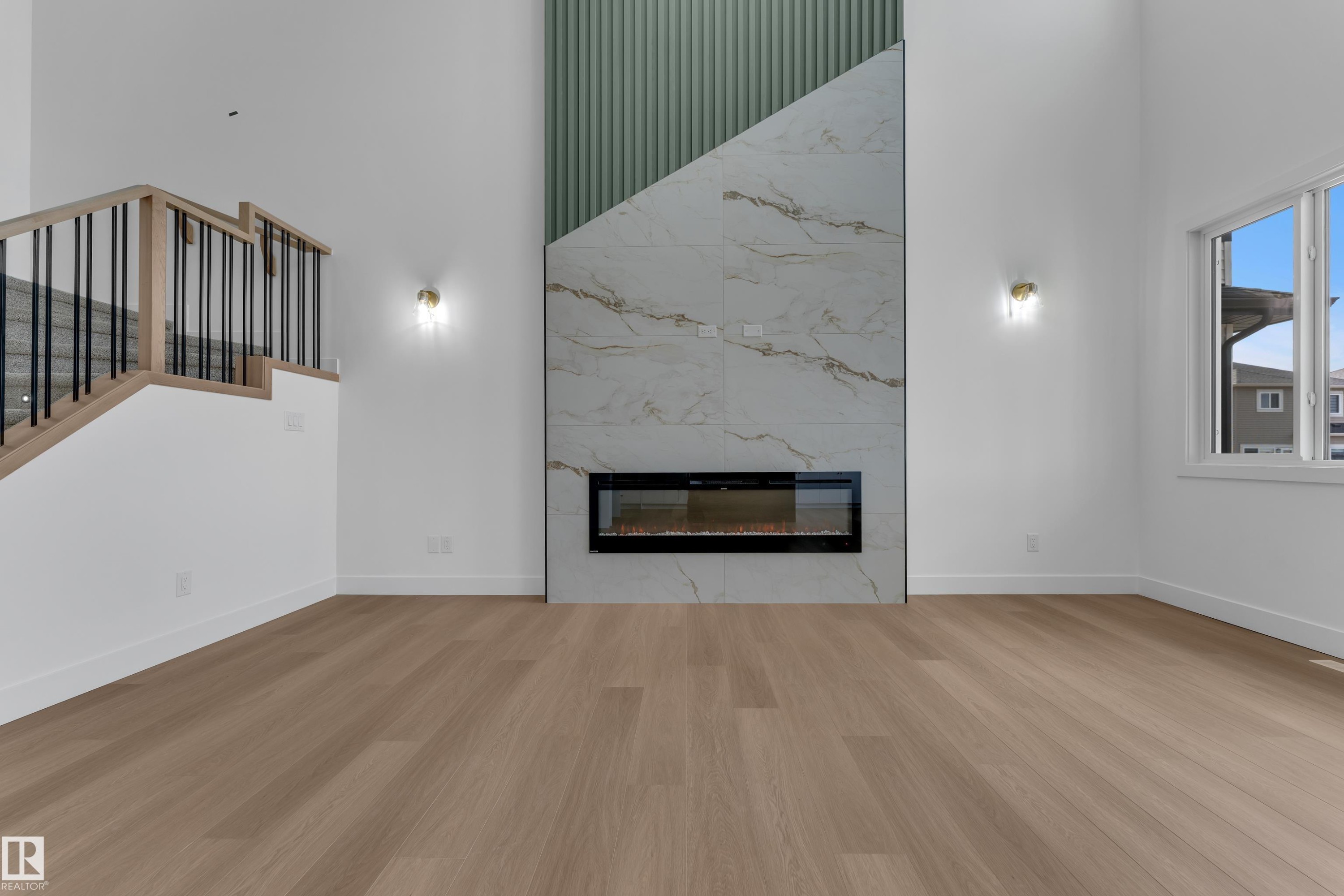 Two-story living area featuring a linear electric fireplace, large format tile surround, and vertical panel accent wall - 4212 63 Street, Beaumont, AB