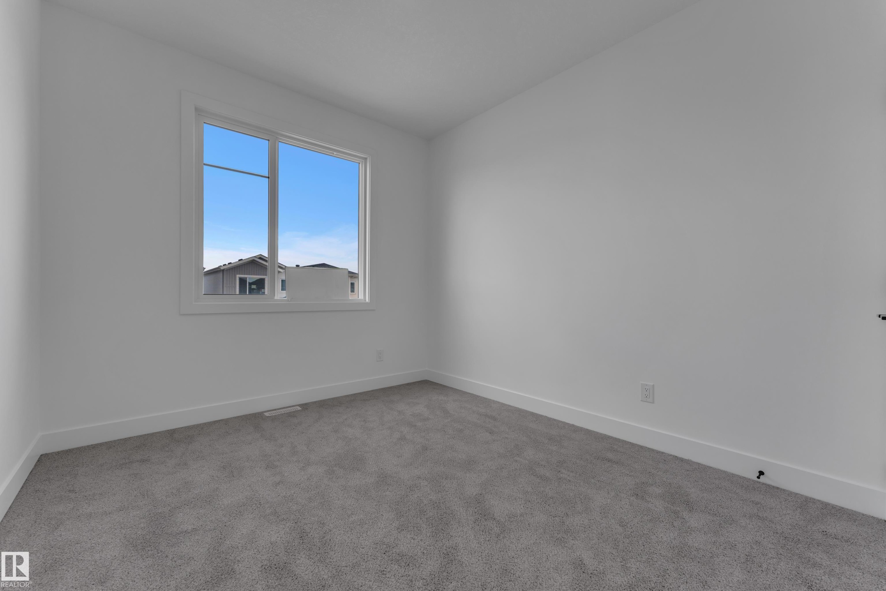 Neutral wall paint, window with white trim, gray carpet flooring - 4212 63 Street, Beaumont, AB