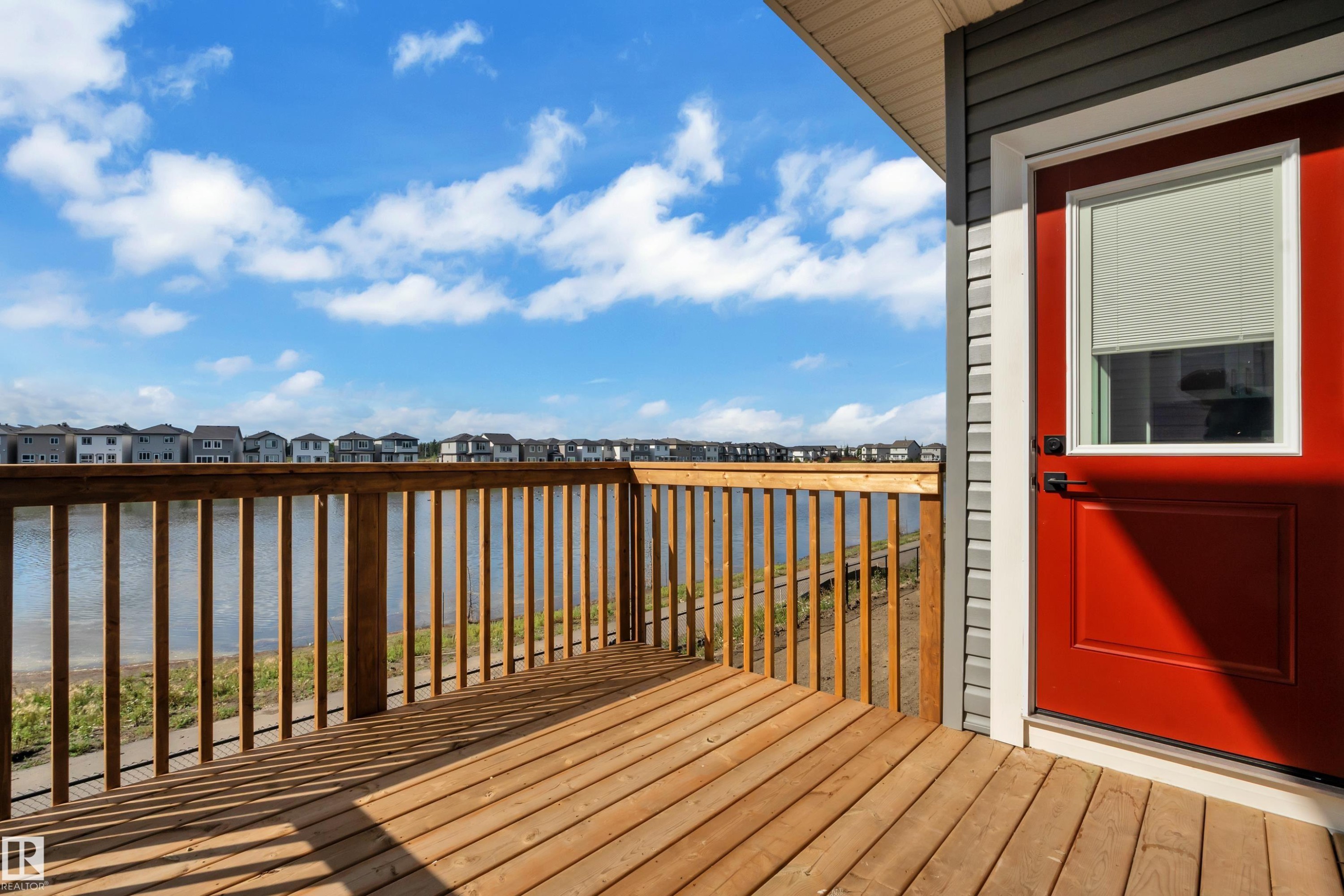 Expansive wood-finish deck with a wood railing, offering a waterfront setting - 4212 63 Street, Beaumont, AB