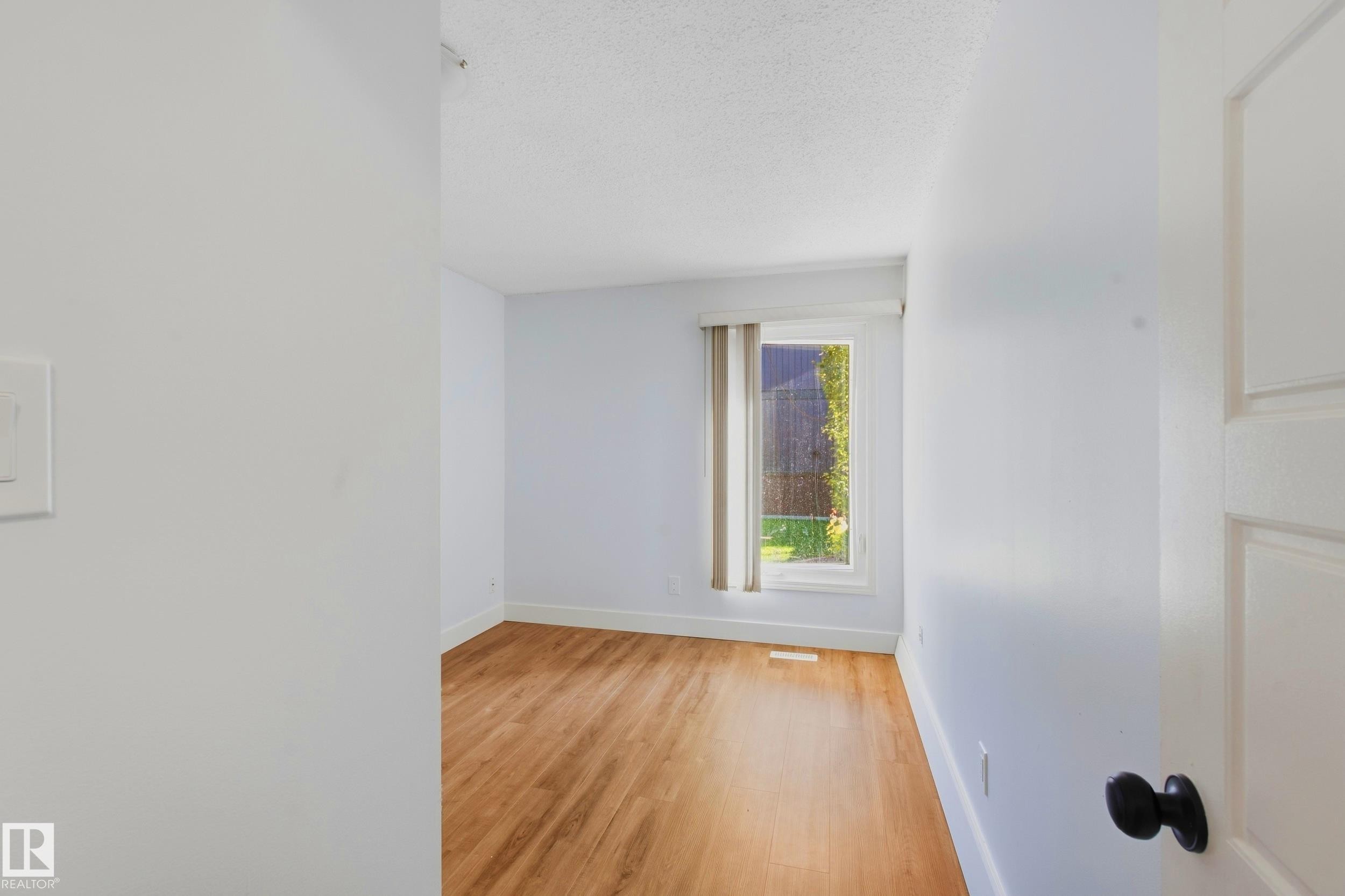 Light wood-finish flooring, white walls, and a large window with vertical blinds - 258 Surrey Gardens Nw, Edmonton, AB