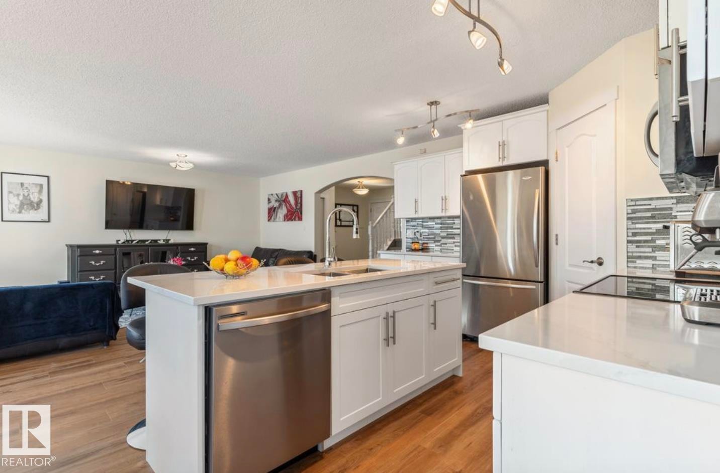 Modern kitchen featuring a central island with an undermount sink and stainless steel dishwasher - 1007 Macewan Close Sw, Edmonton, AB - Indoor Photo Showing Kitchen With Stainless Steel Kitchen