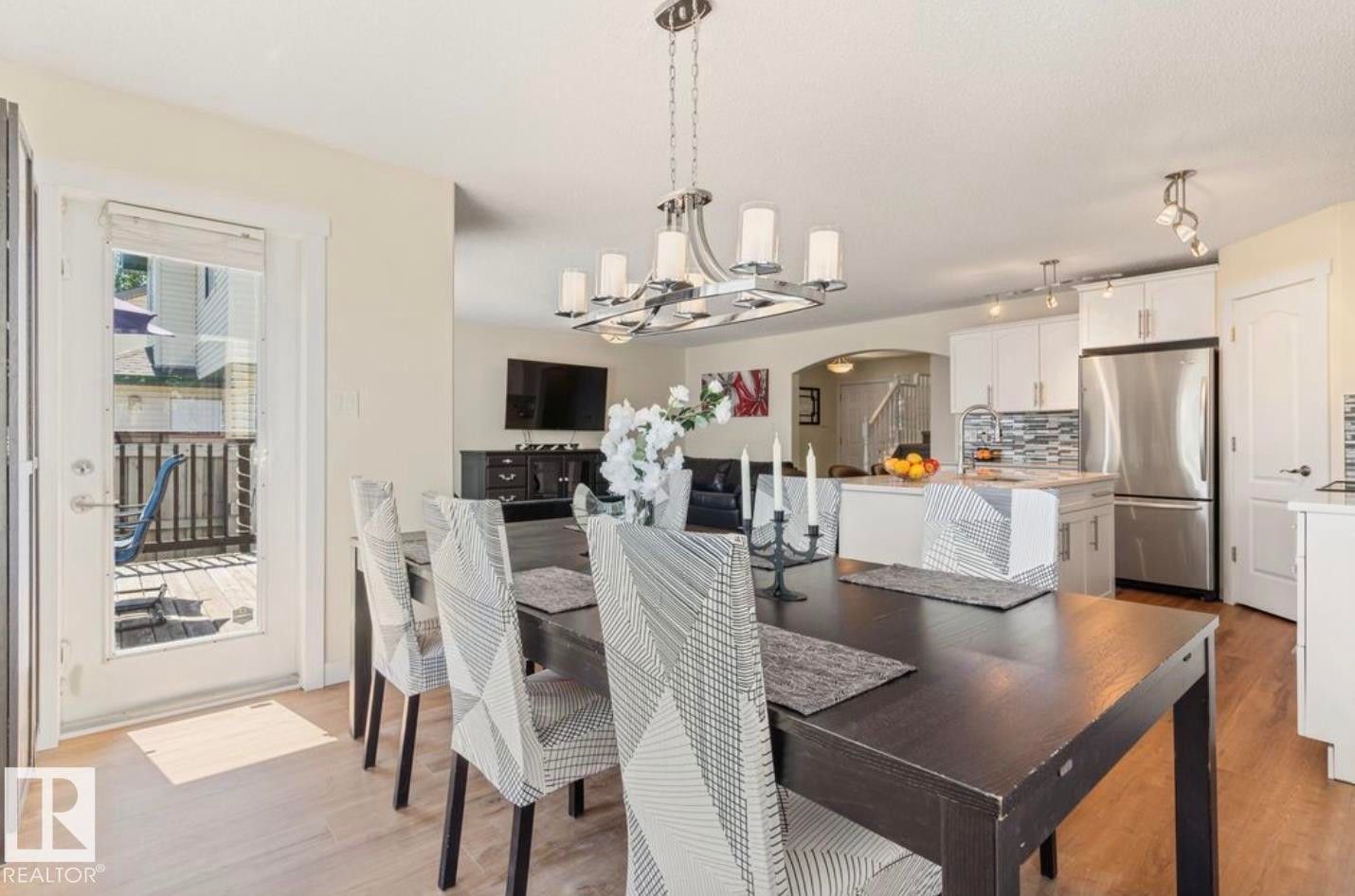 Open-concept dining area featuring wood-finish flooring and a contemporary chandelier - 1007 Macewan Close Sw, Edmonton, AB - Indoor Photo Showing Dining Room