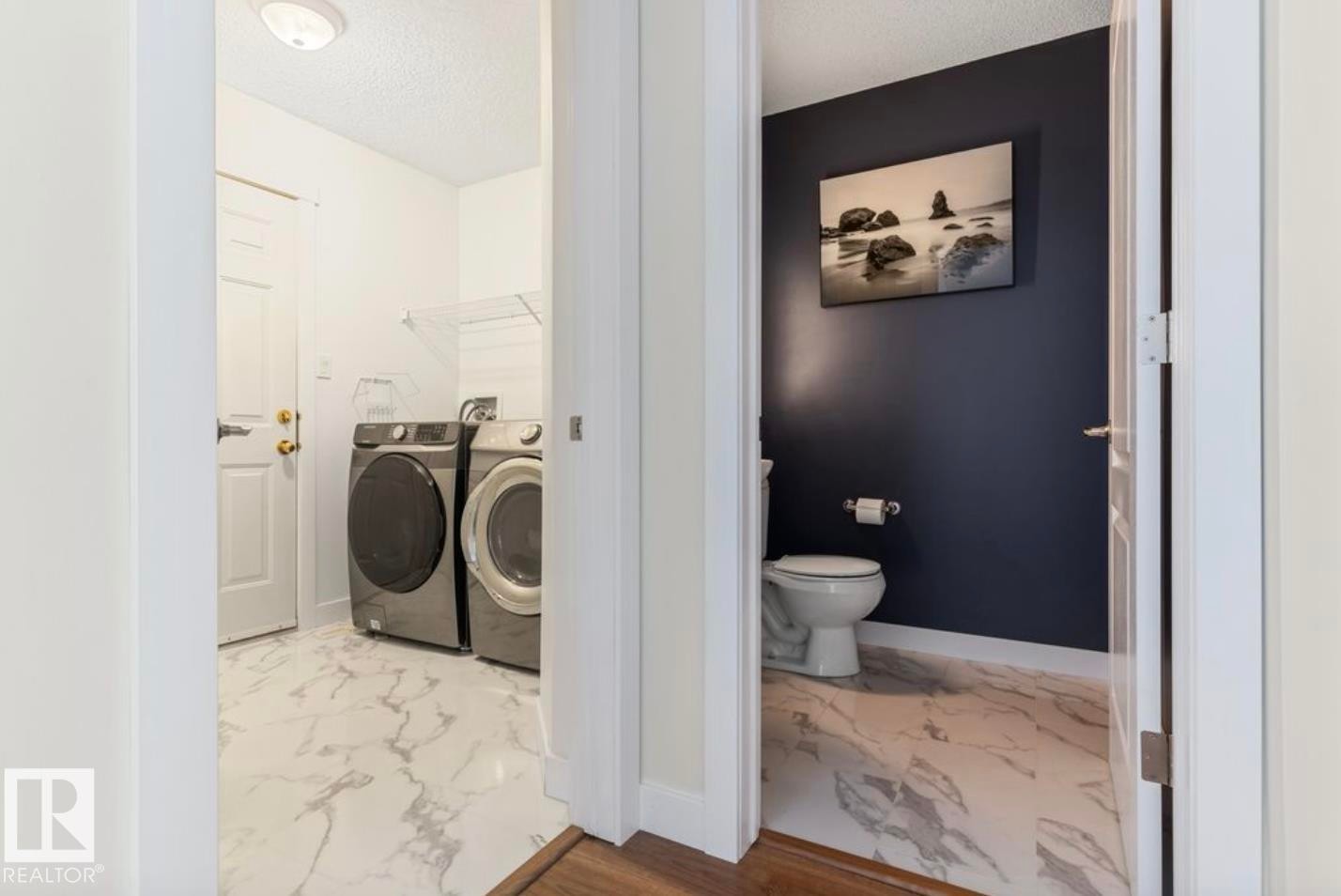 Dedicated laundry area featuring white panel doors, a ceiling-mounted light fixture, and marble-look flooring - 1007 Macewan Close Sw, Edmonton, AB - Indoor Photo Showing Laundry Room