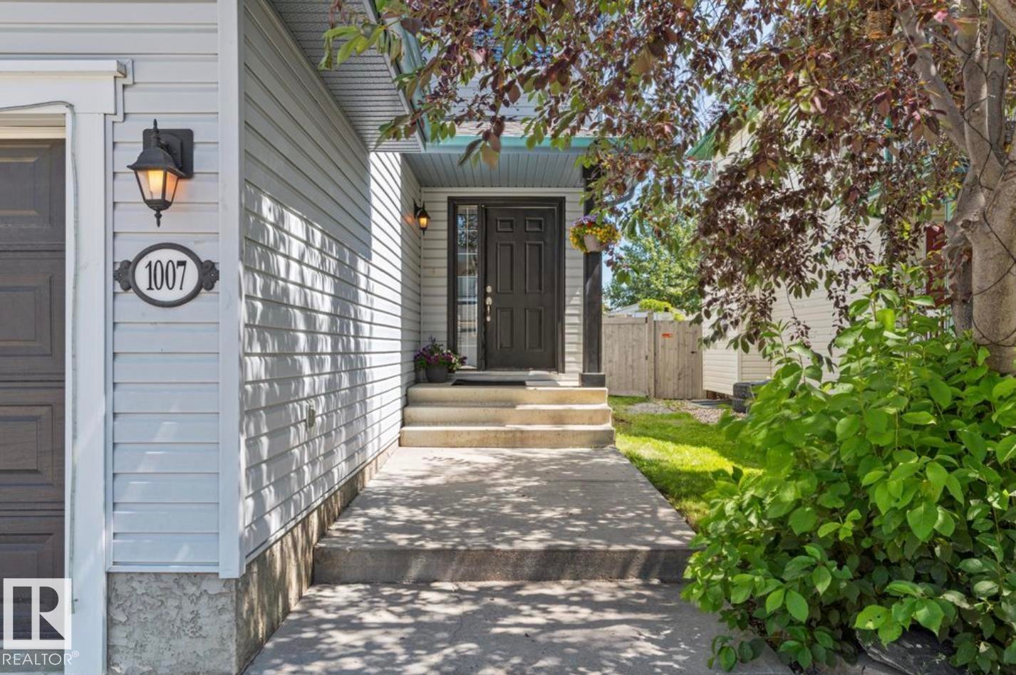 Inviting front entry featuring a dark paneled door and dual exterior wall sconces - 1007 Macewan Close Sw, Edmonton, AB - Outdoor