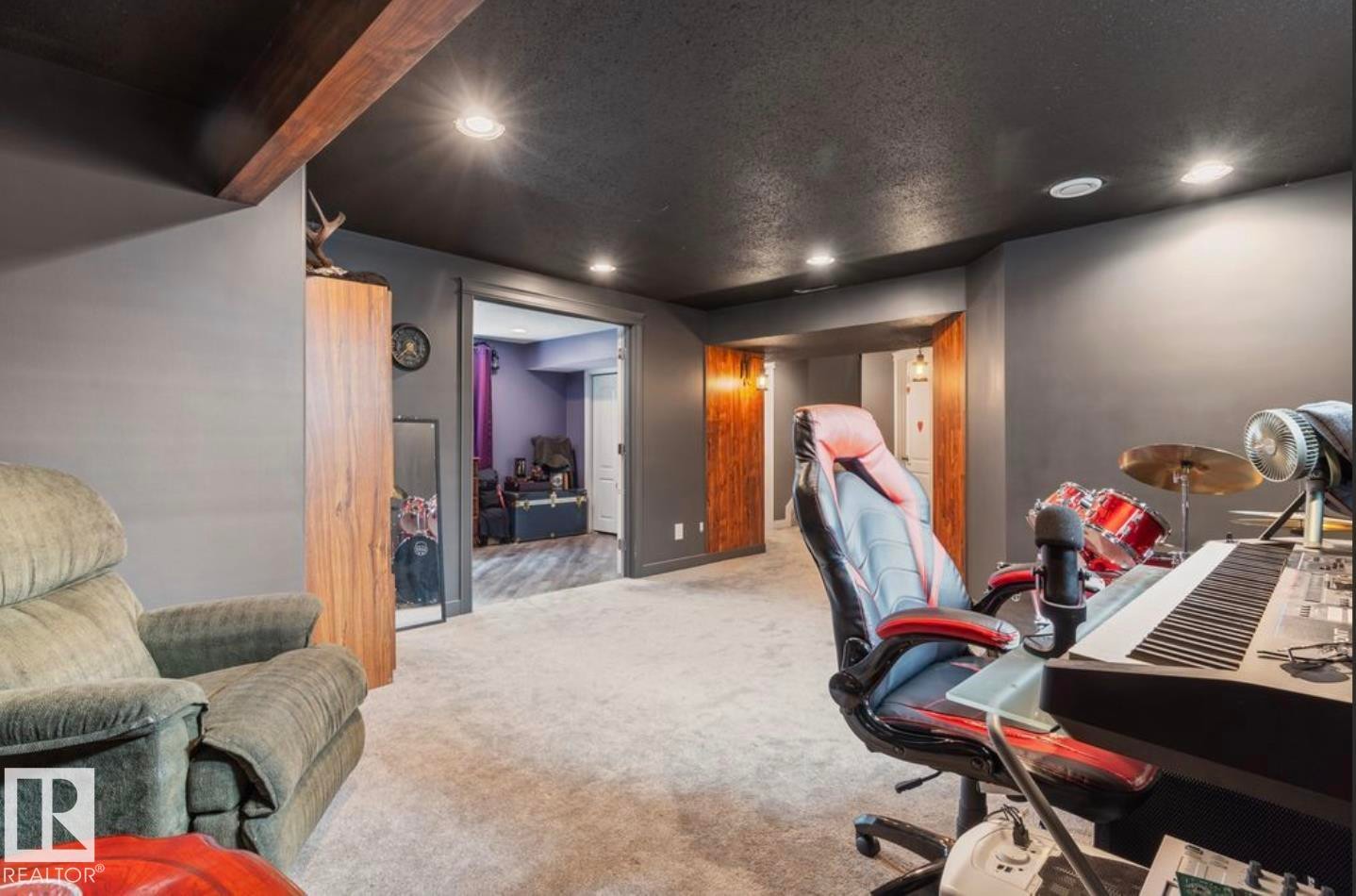Recessed lighting illuminates a spacious room featuring dark gray walls, a contrasting dark ceiling, and light-toned carpeting - 1007 Macewan Close Sw, Edmonton, AB - Indoor