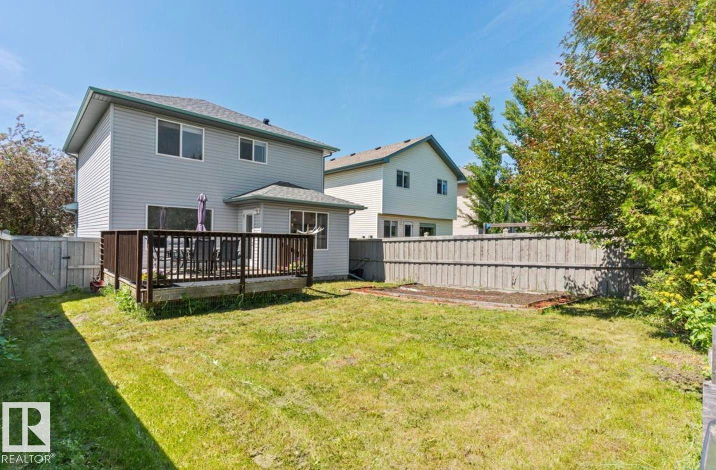 Spacious backyard featuring a substantial wood deck, privacy fencing, and a manicured lawn - 1007 Macewan Close Sw, Edmonton, AB - Outdoor