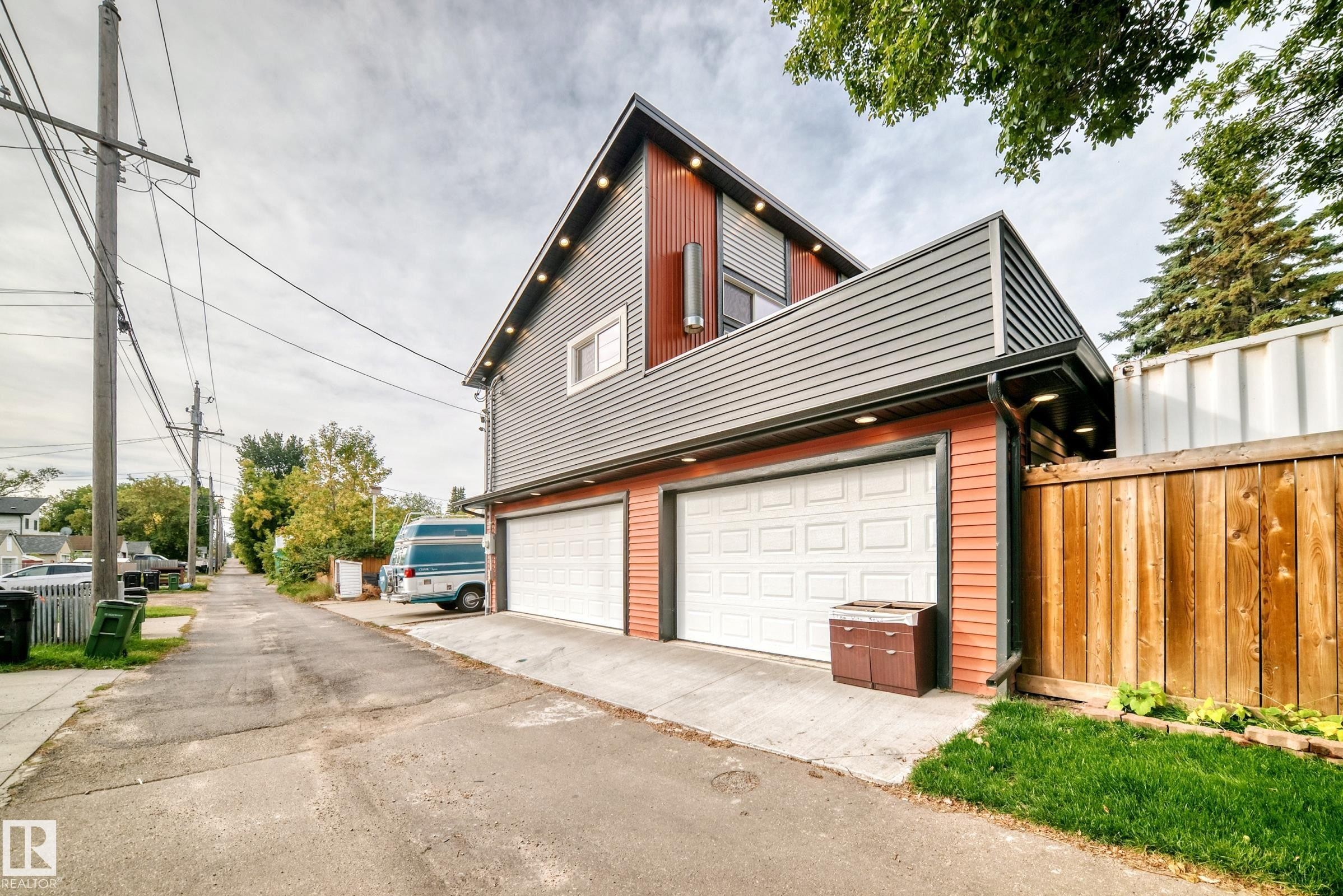 Two-car garage with white panel doors, accented by red-toned horizontal siding and gray vertical siding - 12045 64 Street Nw, Edmonton, AB