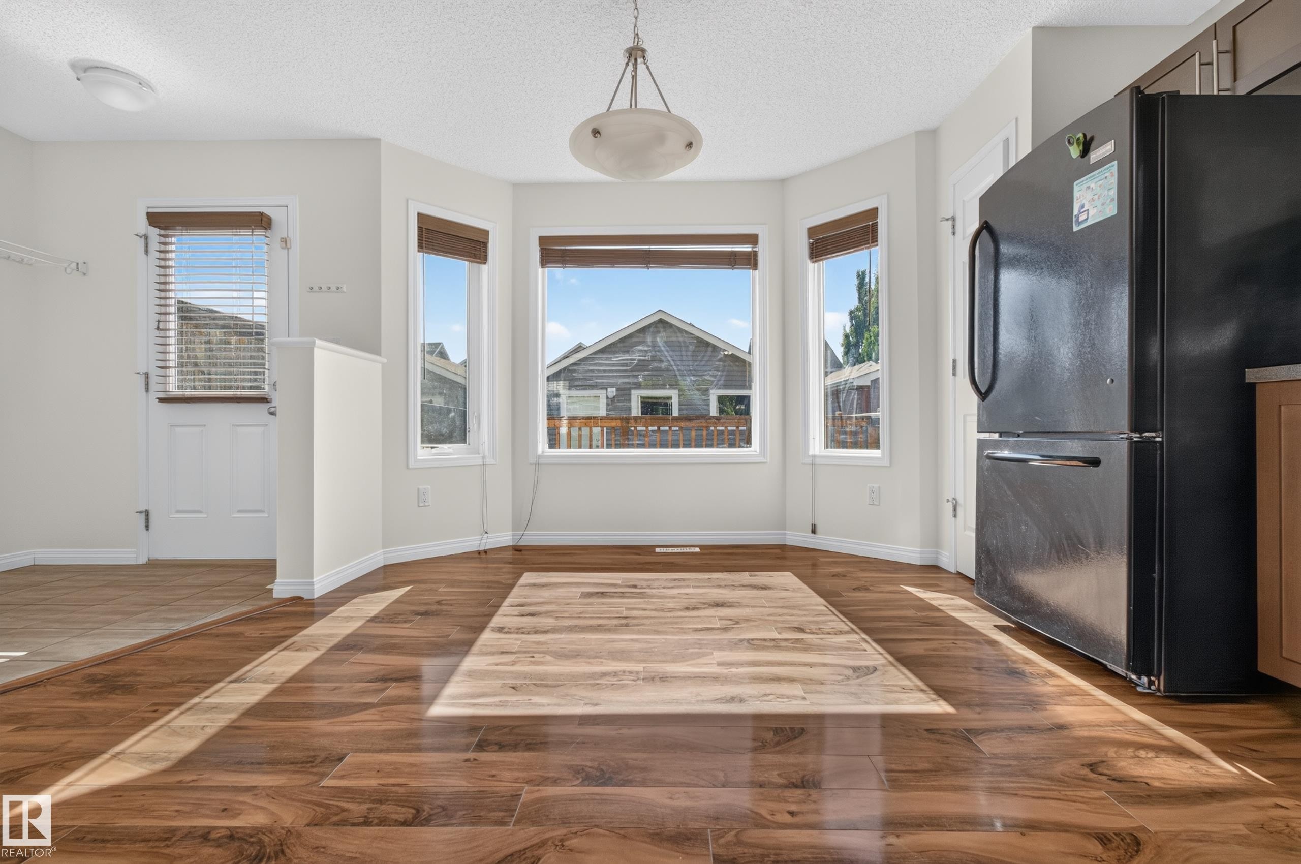 Bay window with multiple panes, wood-finish flooring, white trim, recessed lighting, and a white paneled door - 6933 21A Avenue Sw, Edmonton, AB