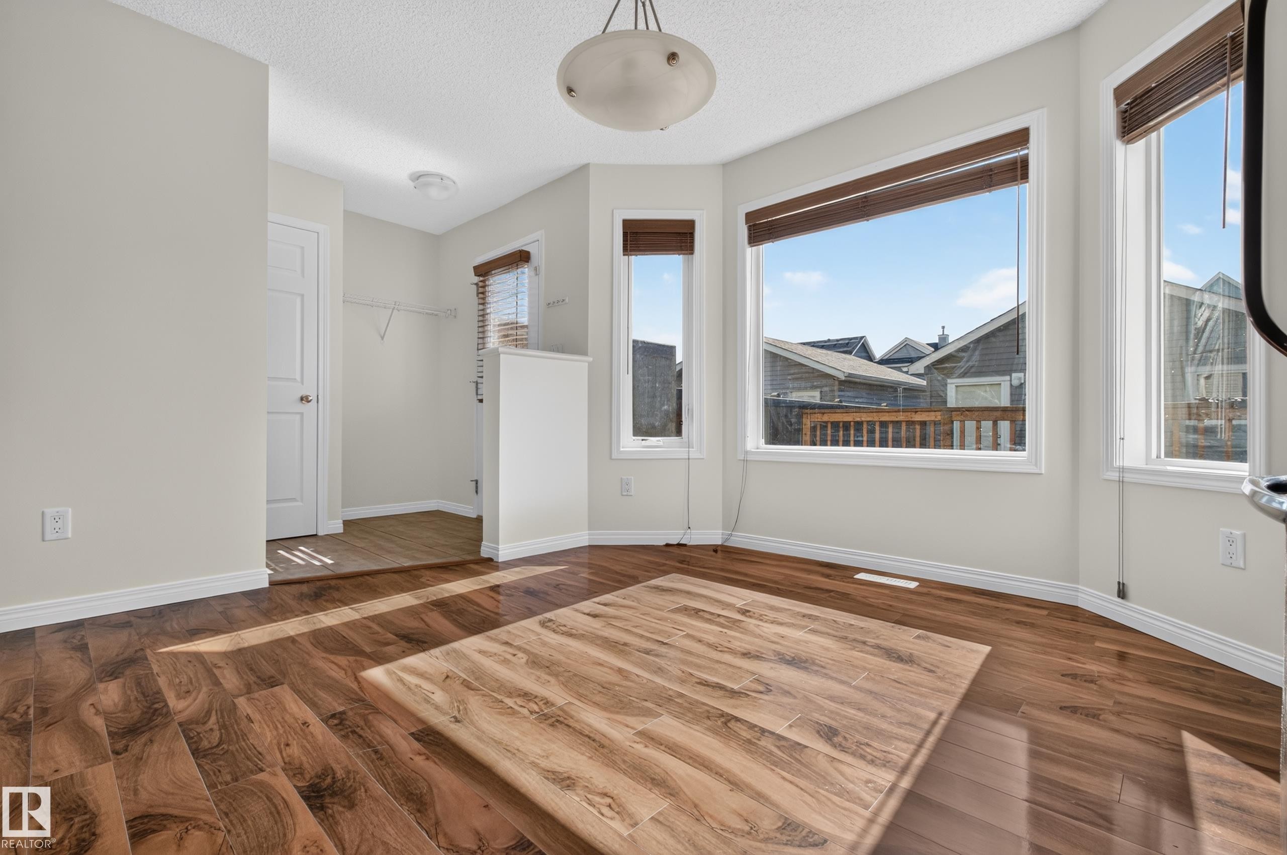 Bay window with multiple panes, wood-finish flooring, white trim, and a semi-flush mount ceiling fixture - 6933 21A Avenue Sw, Edmonton, AB
