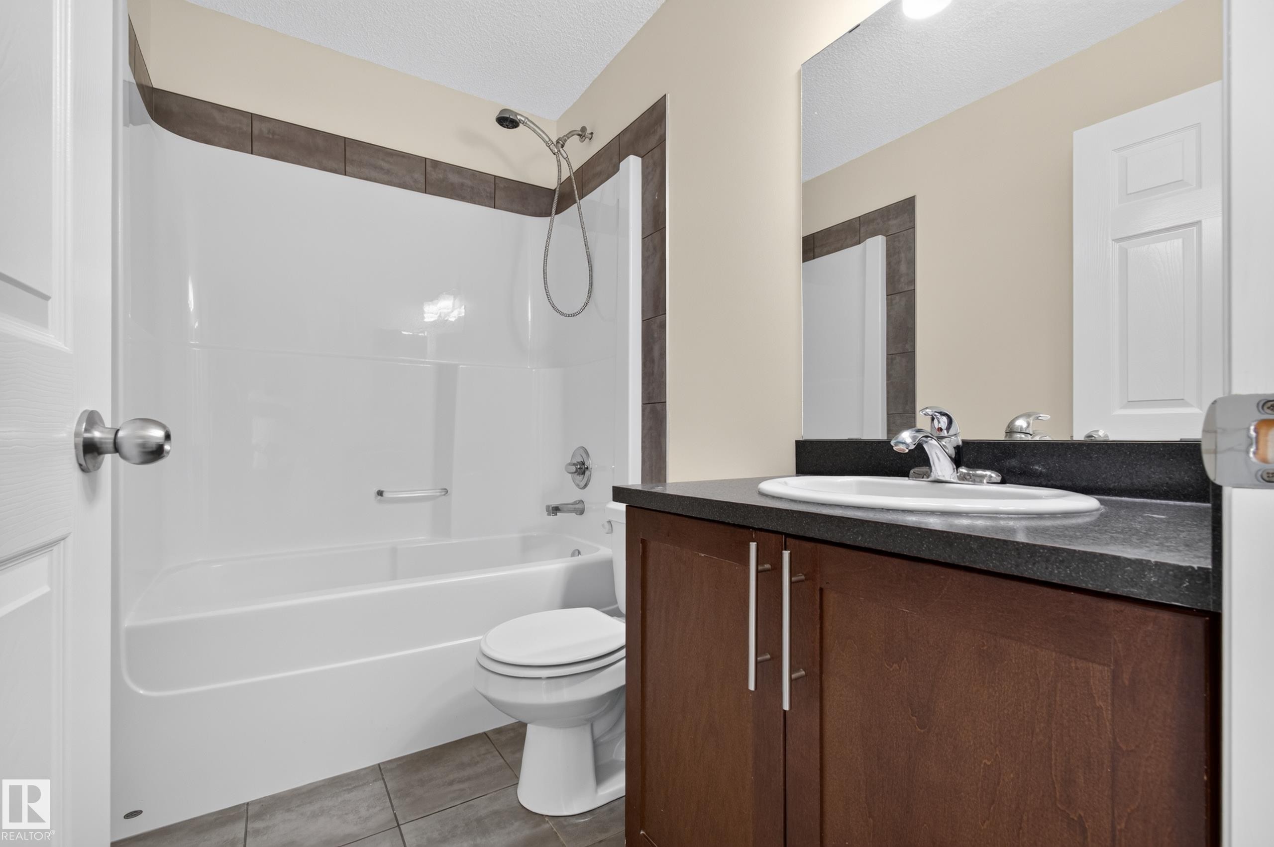 White bathtub and shower combination with a tiled accent border - 6933 21A Avenue Sw, Edmonton, AB