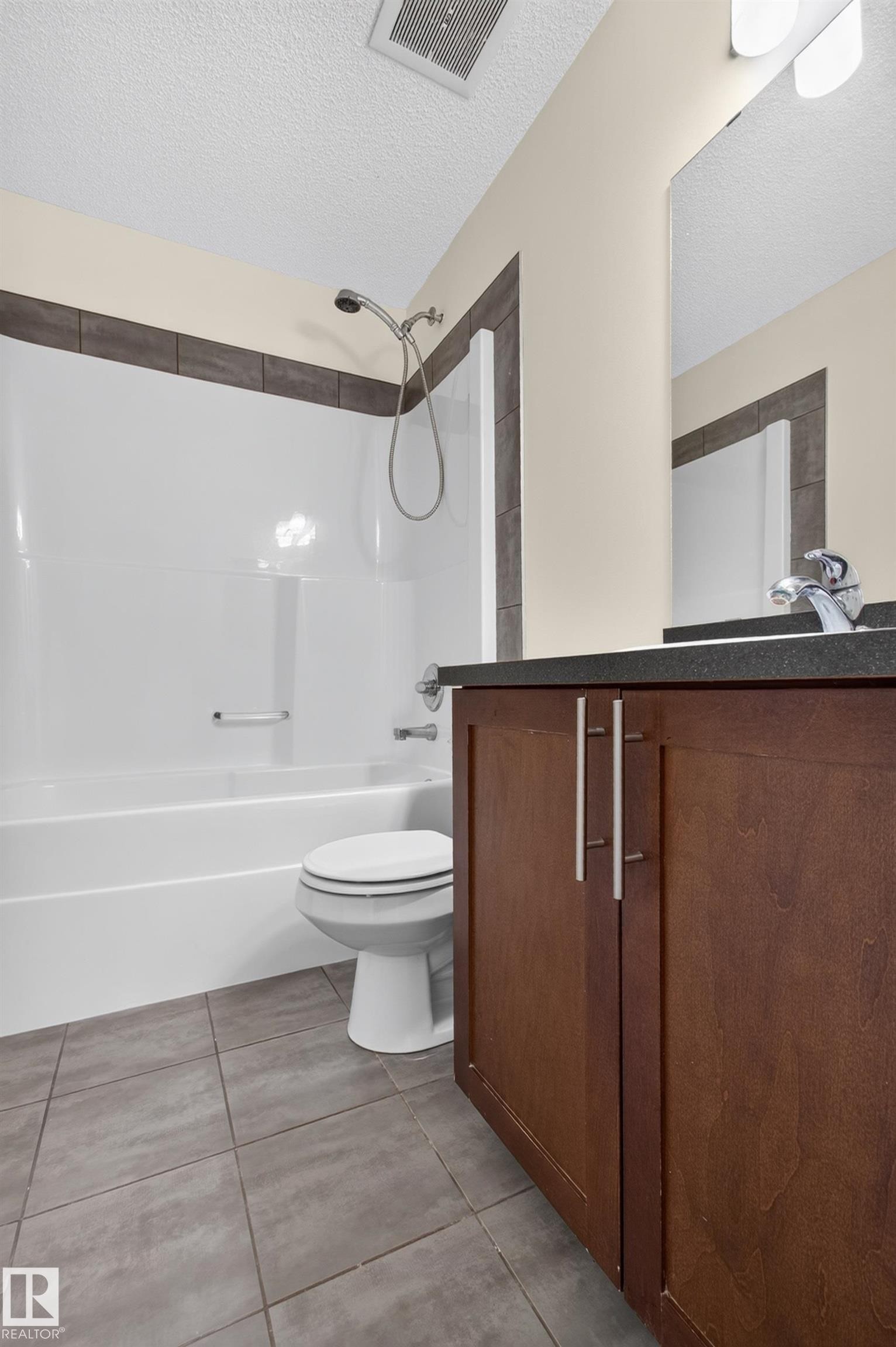 Wood-finish vanity with dual doors and brushed nickel pulls, dark countertop, and undermount sink - 6933 21A Avenue Sw, Edmonton, AB