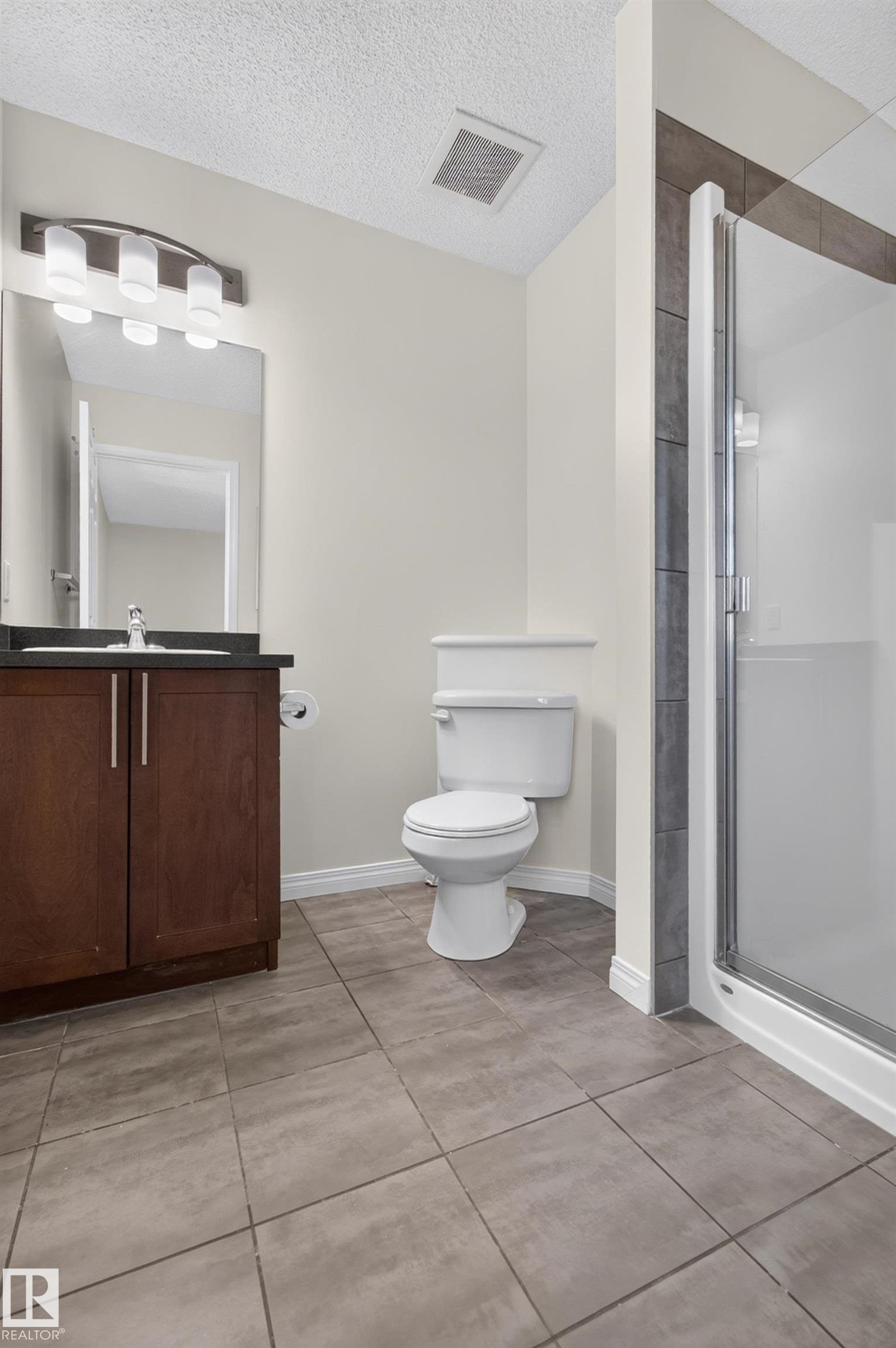 Dark wood-finish vanity with a dark countertop and undermount sink - 6933 21A Avenue Sw, Edmonton, AB