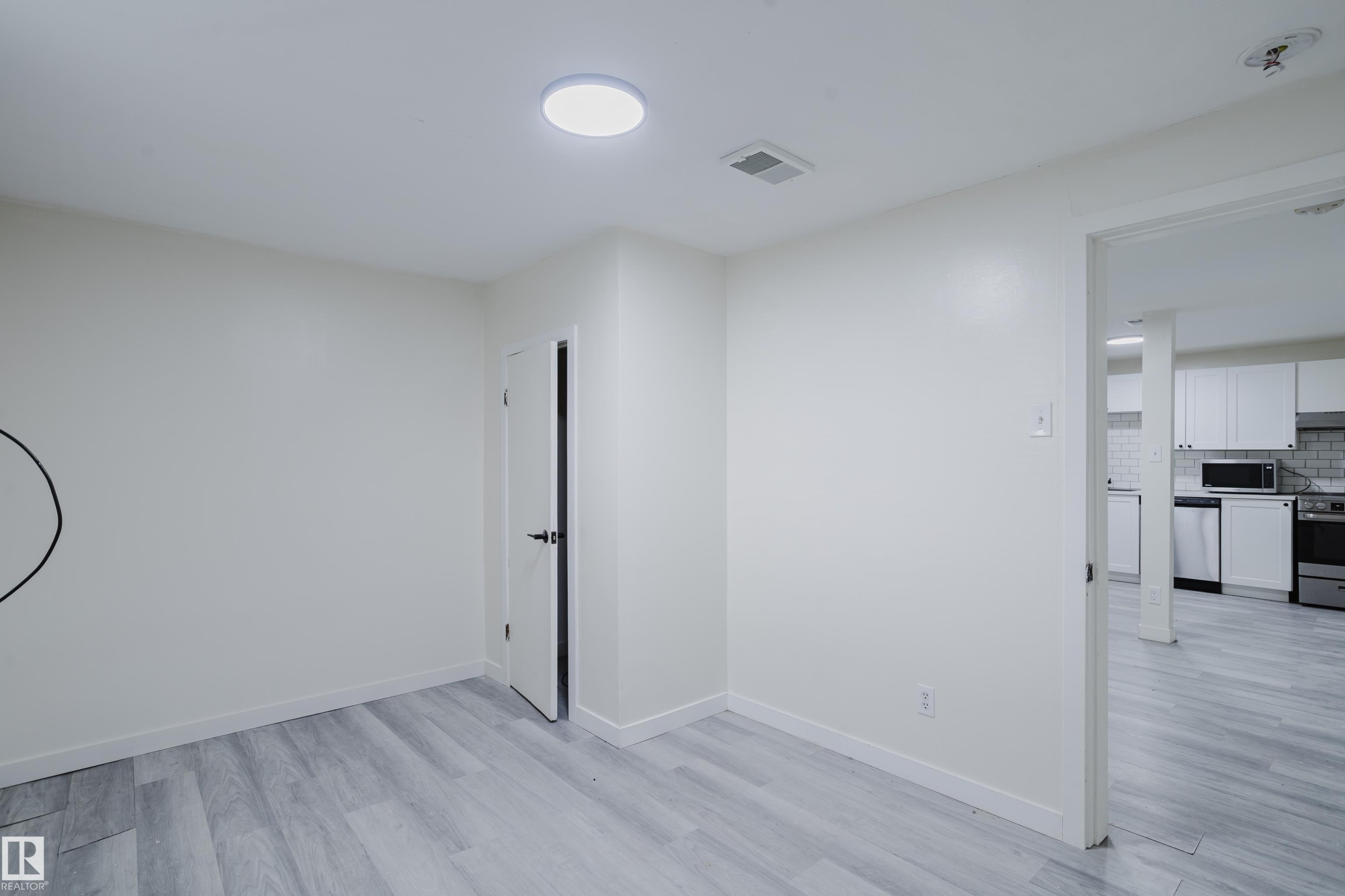 Recessed ceiling light, light wood-finish flooring, white walls, and a white interior door with black hardware - 11134 11138 116 Street Nw, Edmonton, AB