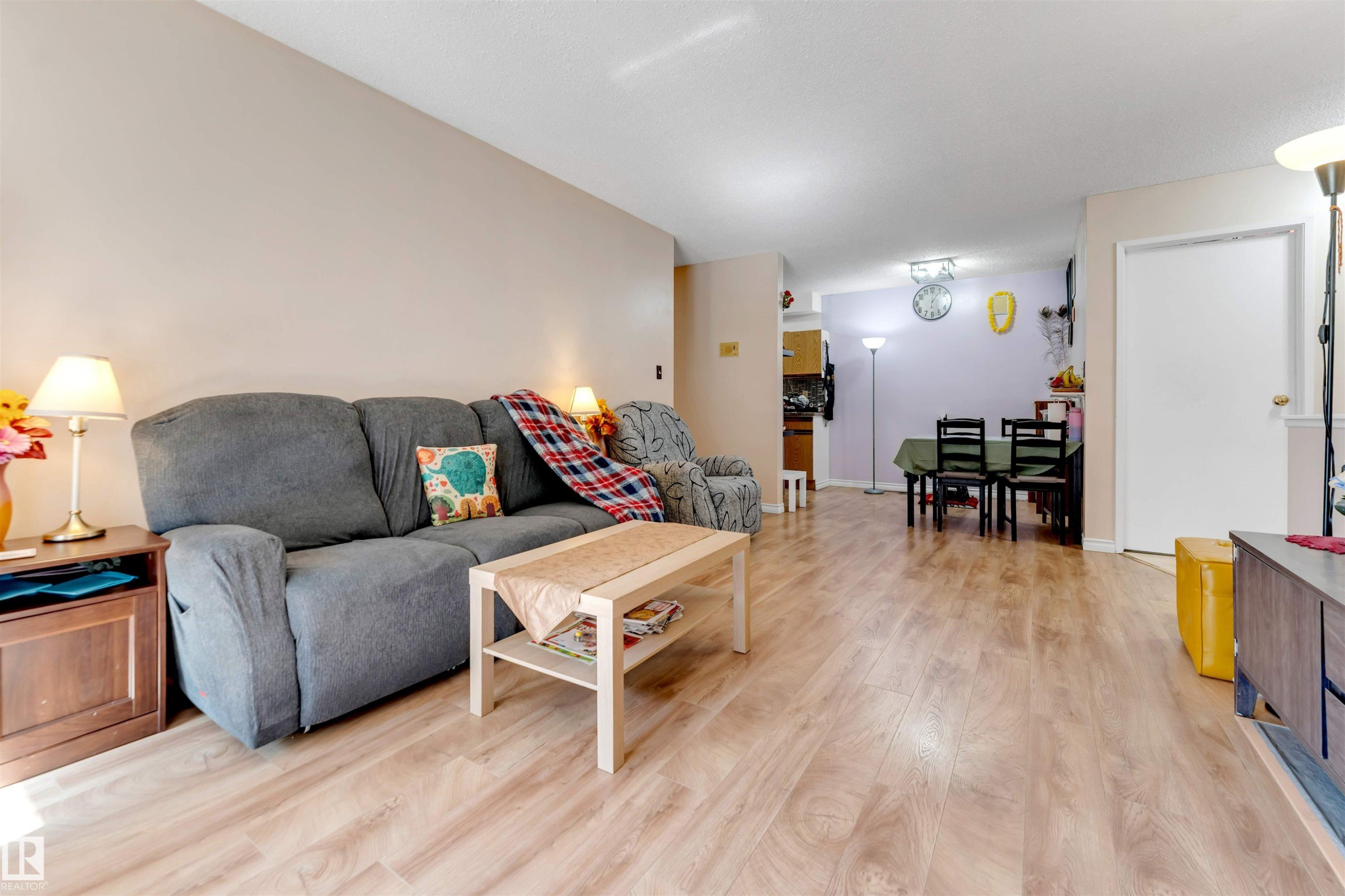 Light wood-finish flooring extends through the living and dining areas - #101 49 Akins Dr, St. Albert, AB