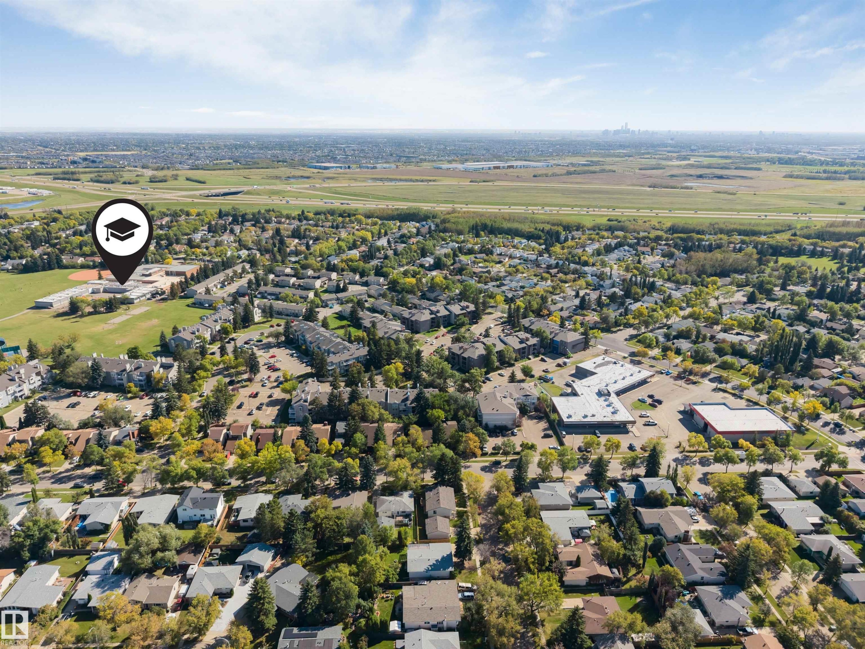Expansive aerial encompassing a residential area, educational facility with athletic fields, and commercial buildings - #101 49 Akins Dr, St. Albert, AB