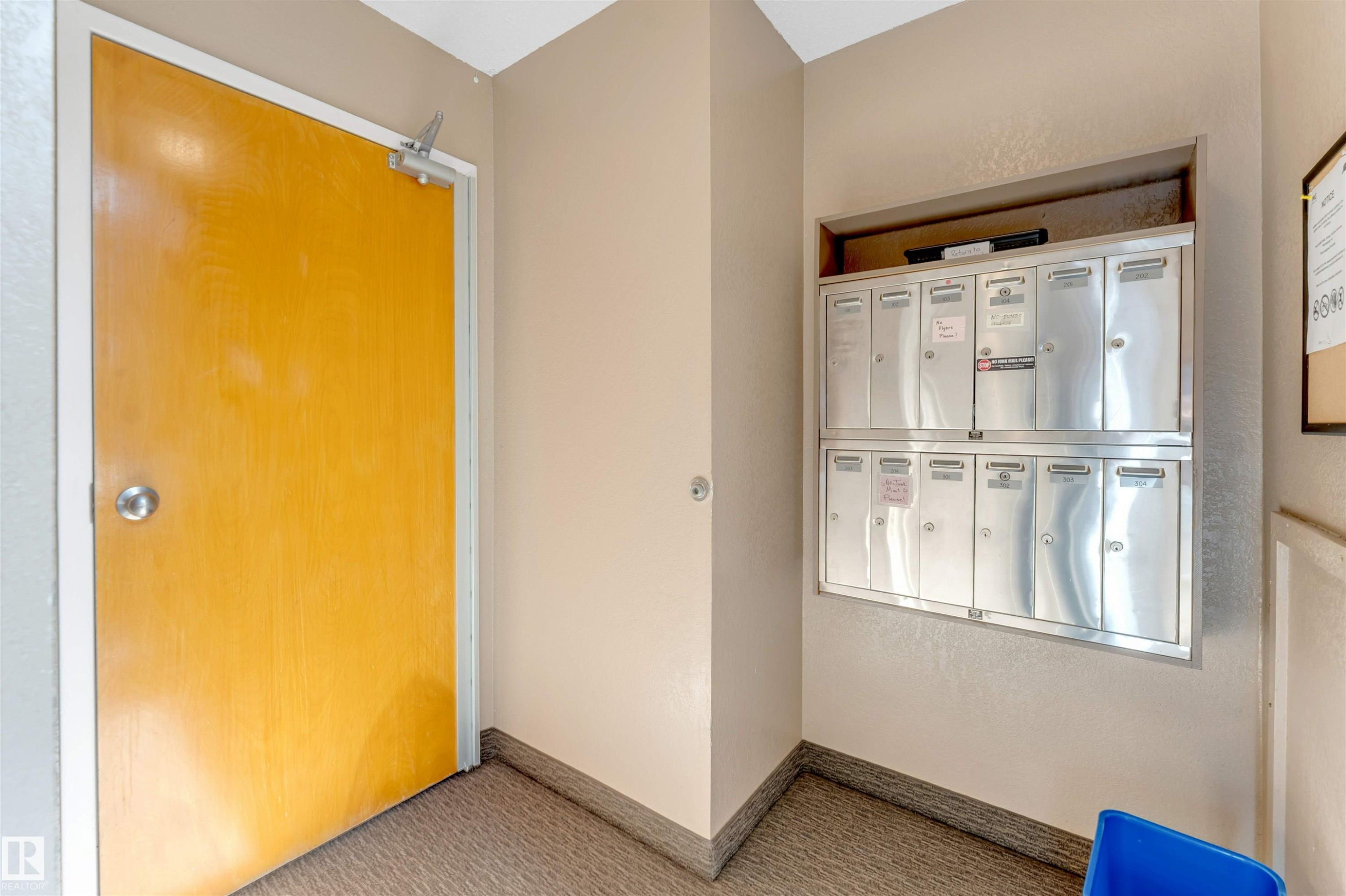 Carpeted entry with textured wall finish and a built-in mailbox system - #101 49 Akins Dr, St. Albert, AB