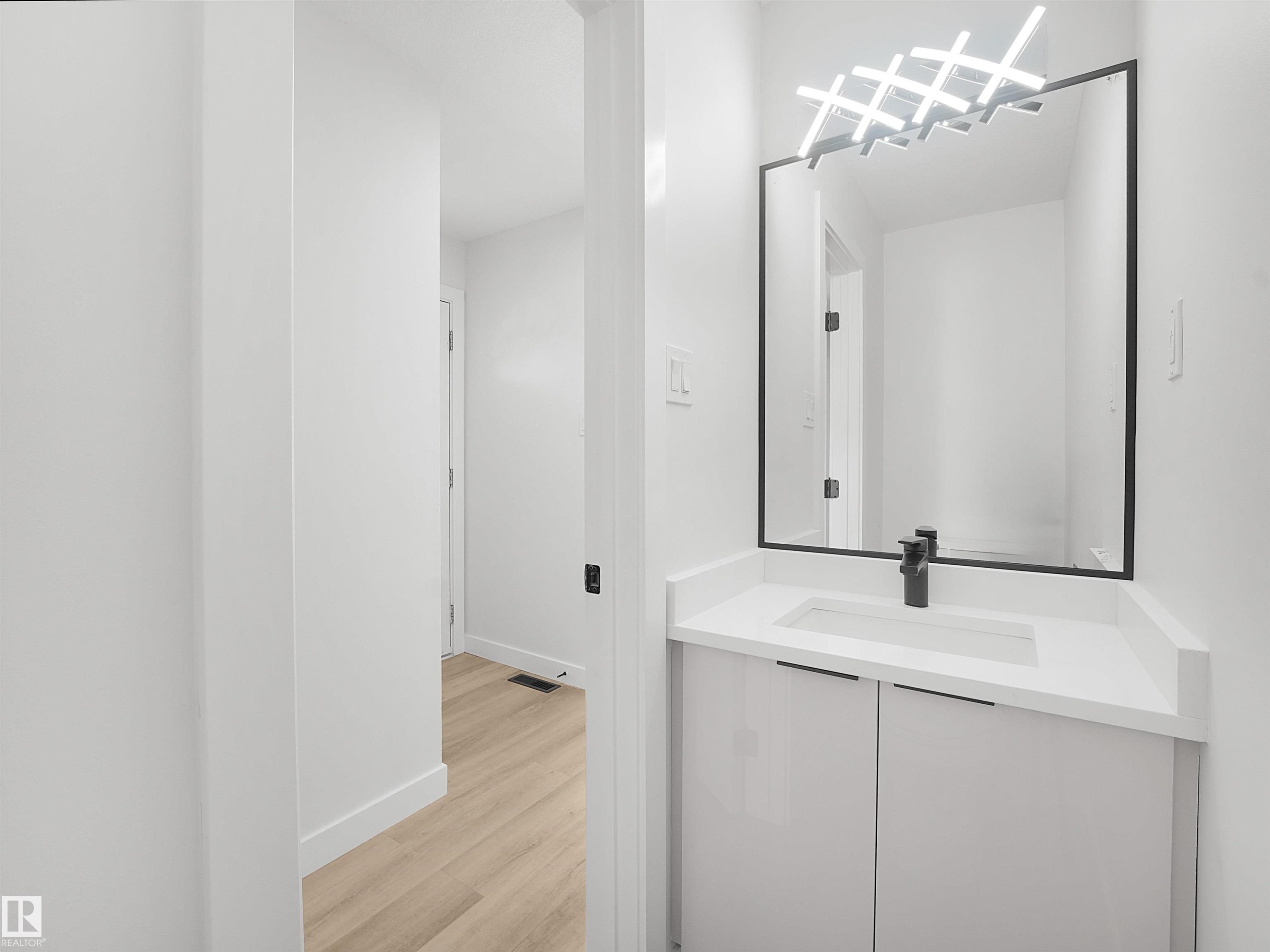 White vanity with an integrated rectangular sink, matte black faucet, and a black-framed mirror - 12C Twin Terrace Nw, Edmonton, AB