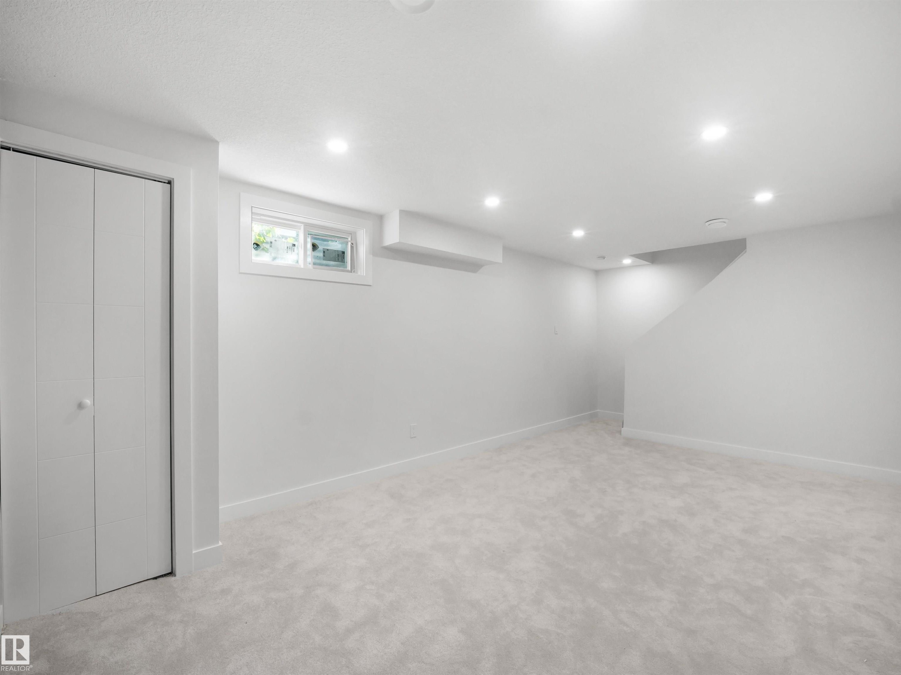 Recessed ceiling lighting, light gray wall paint, light gray carpeting, bi-fold closet doors, and a window - 12C Twin Terrace Nw, Edmonton, AB