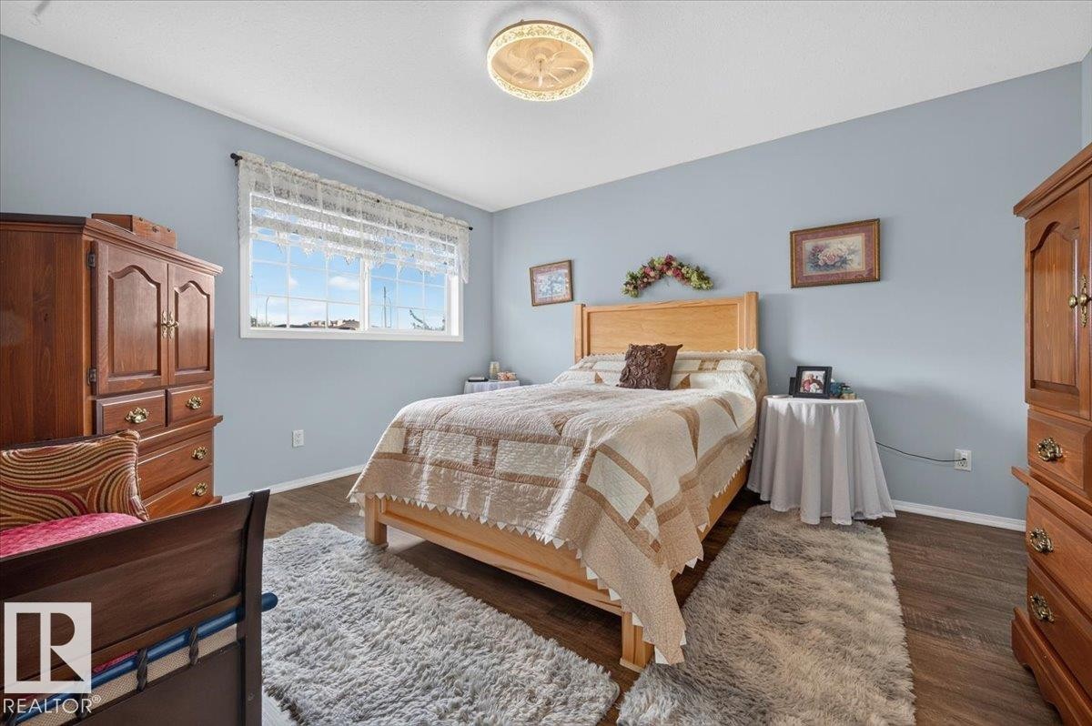Spacious room featuring wood-finish flooring and a central ceiling light fixture - #125 4610 50 Ave, Stony Plain, AB