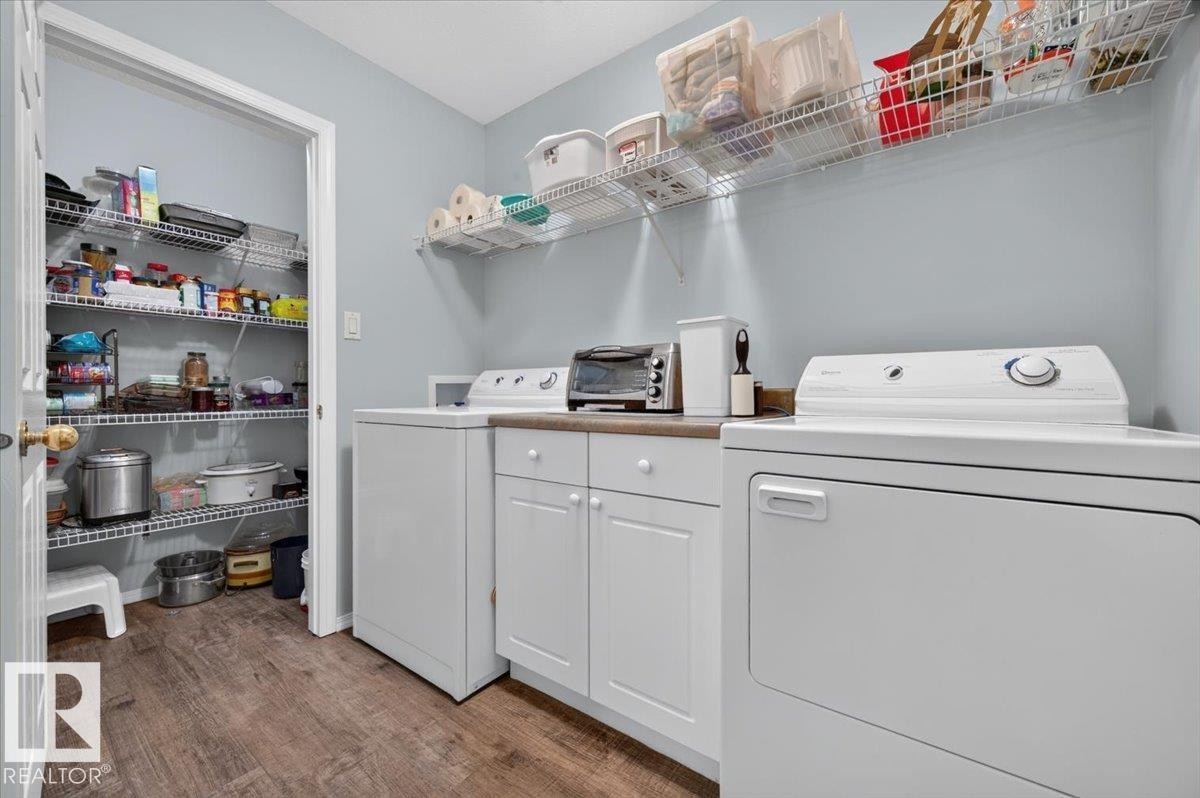 Laundry area featuring wood-finish flooring, white cabinetry, and a countertop workspace - #125 4610 50 Ave, Stony Plain, AB