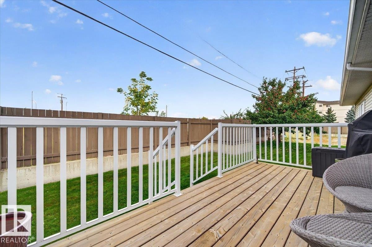Wood-plank deck with white railings, offering outdoor living space - #125 4610 50 Ave, Stony Plain, AB