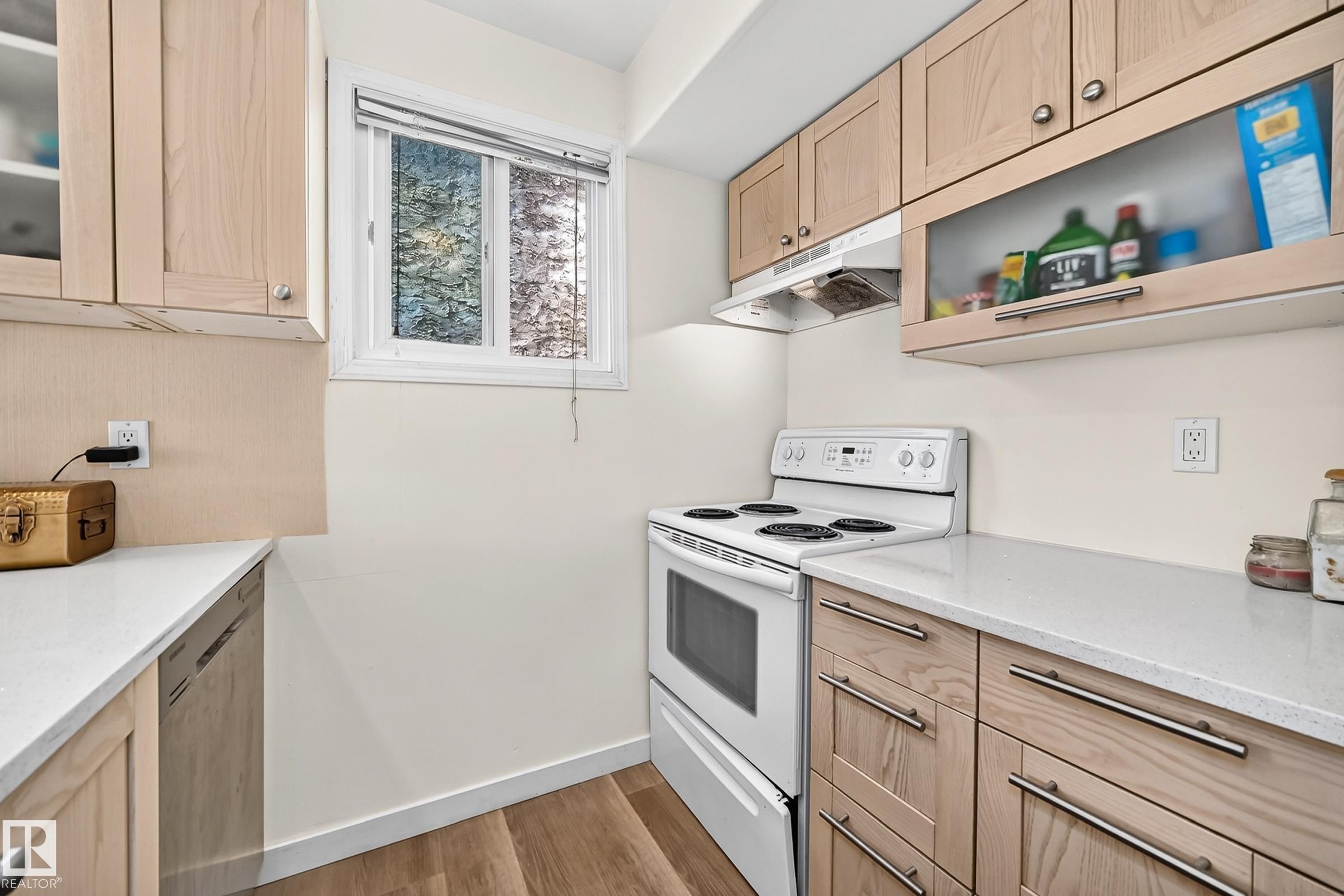 Wood-finish flooring with light-toned cabinetry, light countertops, and a white range - 161 Lancaster Terrace Nw, Edmonton, AB