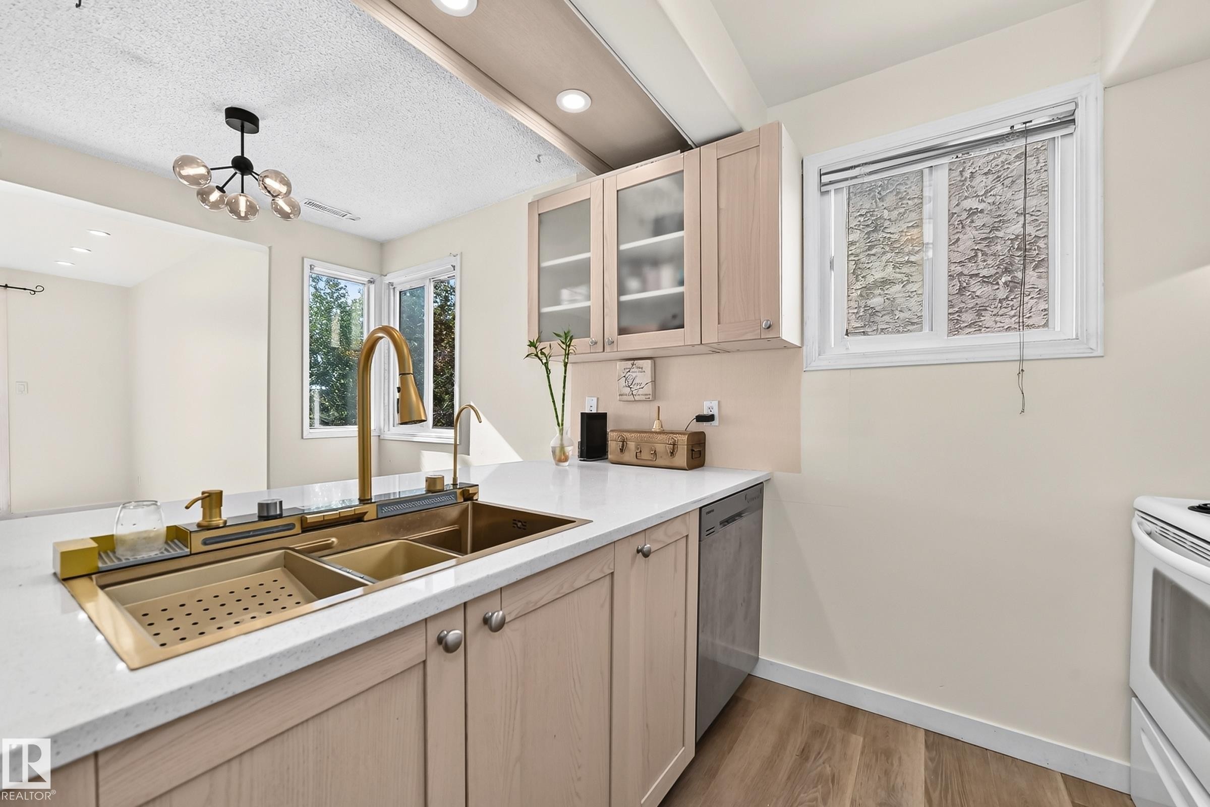 Integrated gold-finish sink with a matching faucet, light wood-finish cabinetry, white countertops, and wood-finish flooring - 161 Lancaster Terrace Nw, Edmonton, AB