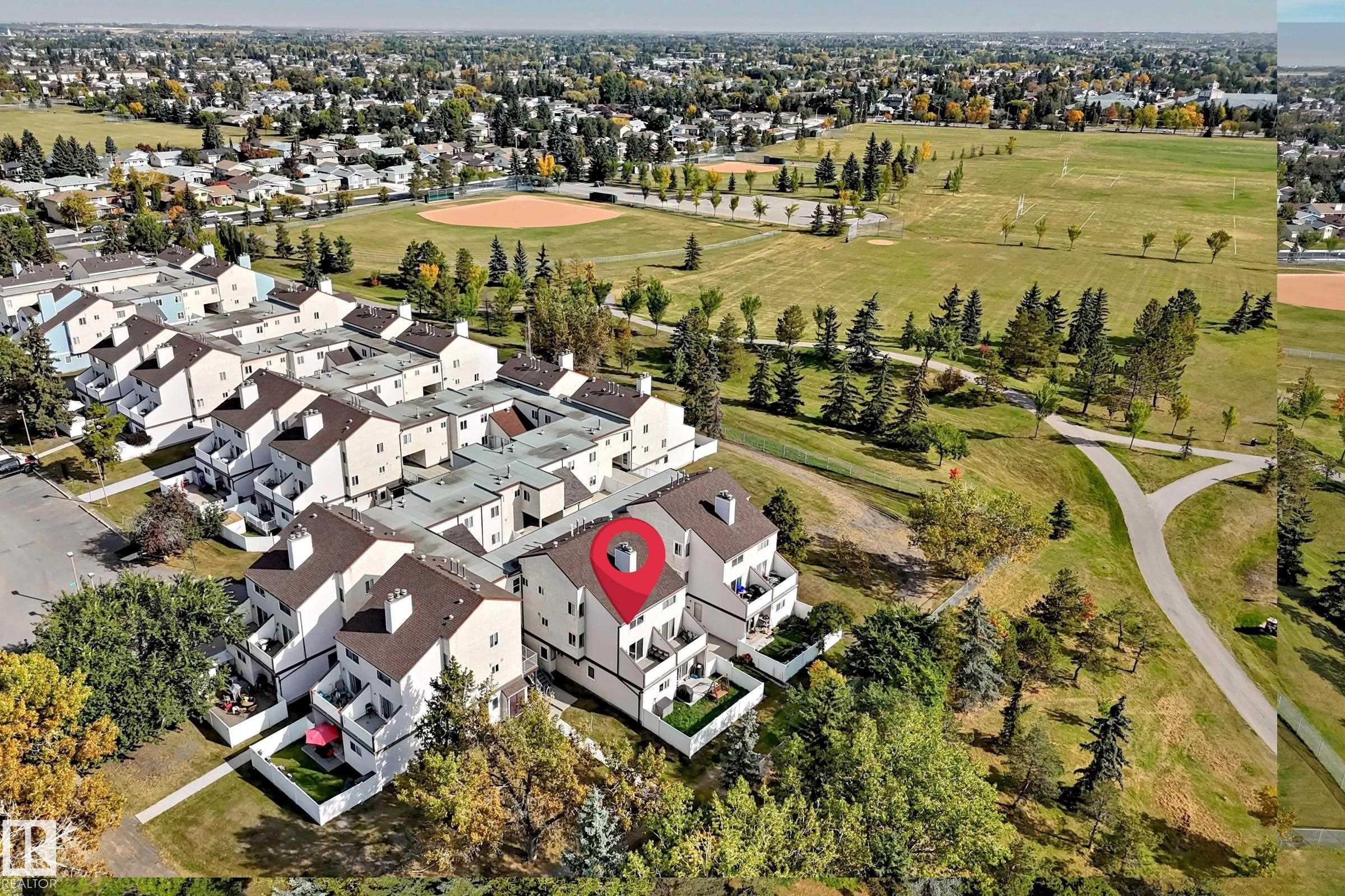 Townhouse community featuring private balconies, individual patios, and direct access to expansive green spaces with paved pathways - 161 Lancaster Terrace Nw, Edmonton, AB