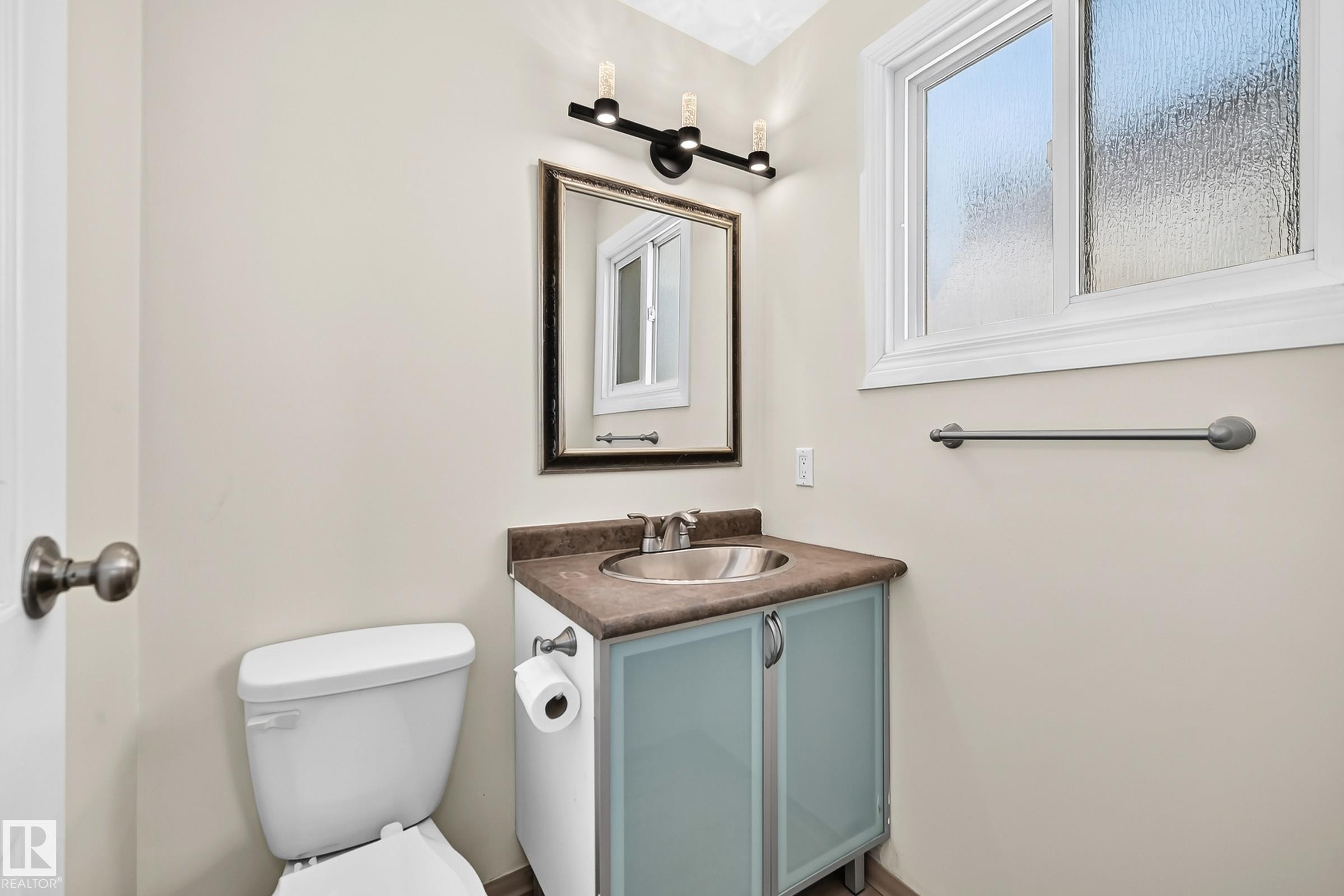 Bathroom with a single-sink vanity featuring a countertop, integrated sink, and cabinet storage - 161 Lancaster Terrace Nw, Edmonton, AB