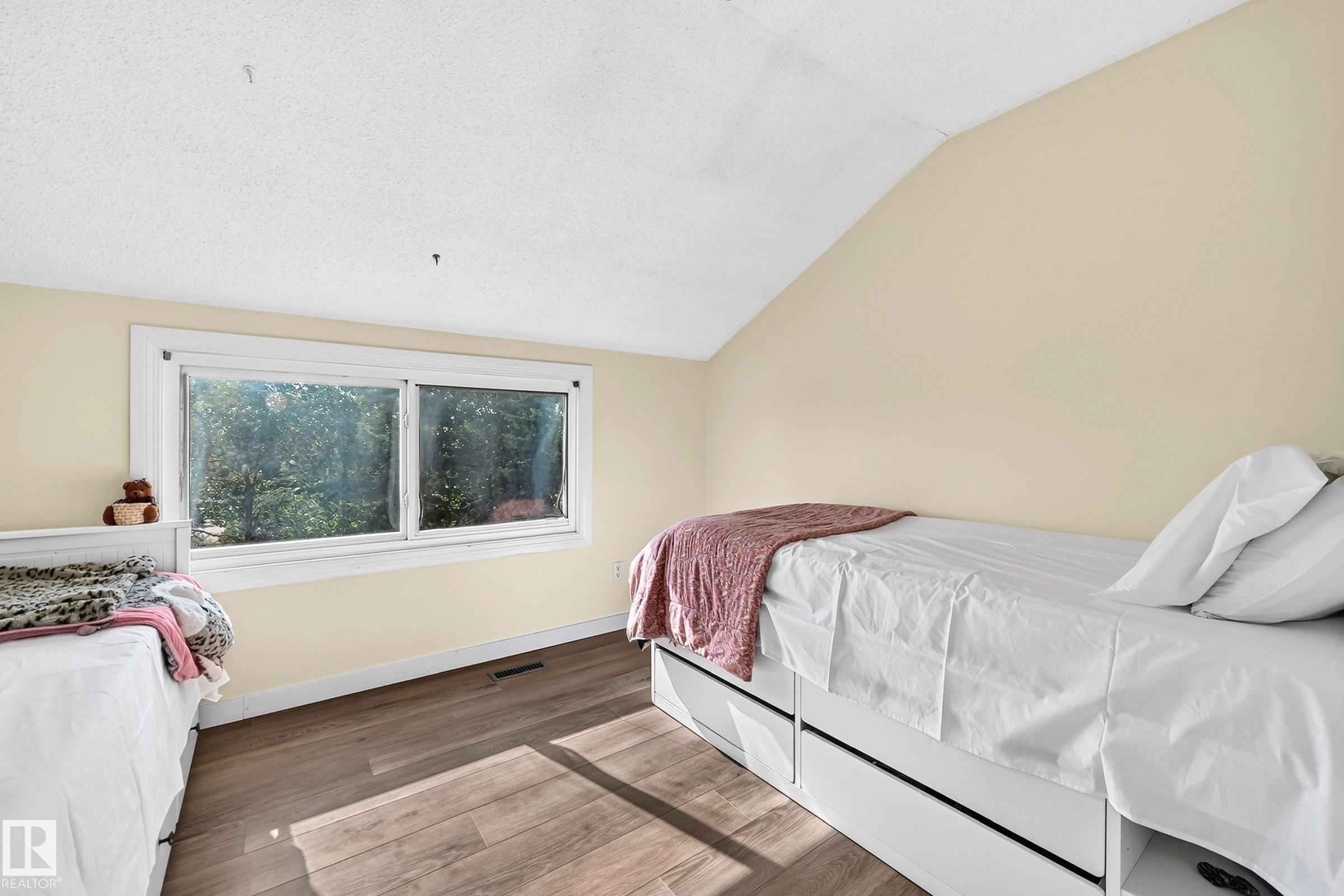 Sloped ceiling, wood-finish flooring, and white trim window - 161 Lancaster Terrace Nw, Edmonton, AB