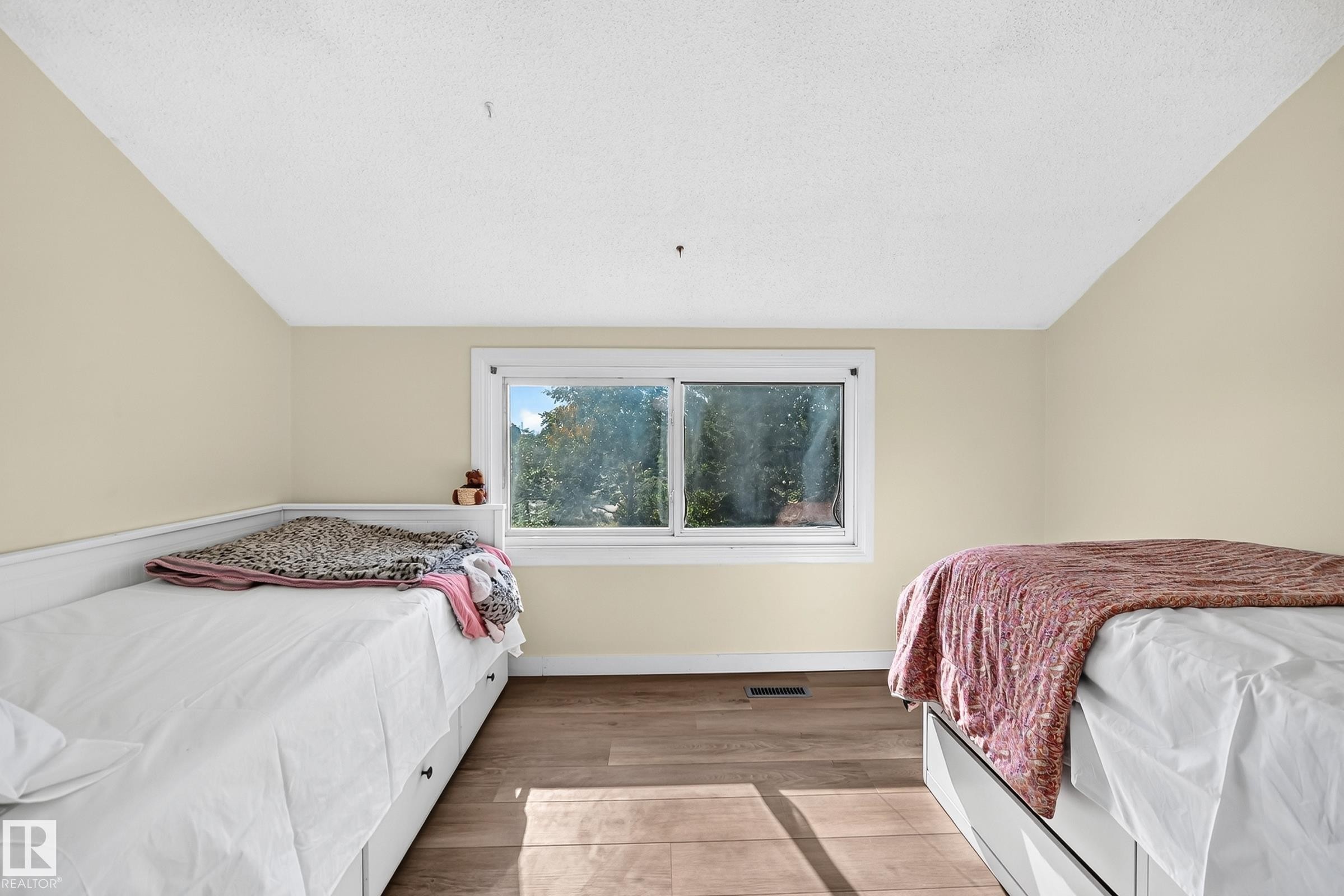 Room featuring wood-finish flooring, a window with white trim, and a built-in daybed with storage drawers - 161 Lancaster Terrace Nw, Edmonton, AB